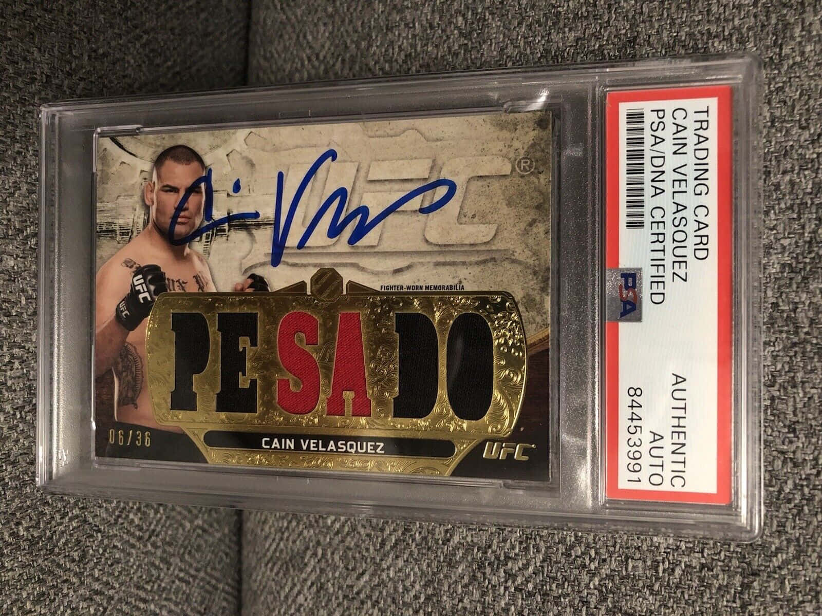 簽名UFC交易卡，Cain Velasquez，喺PSA認證保護殼入面，灰色表面。