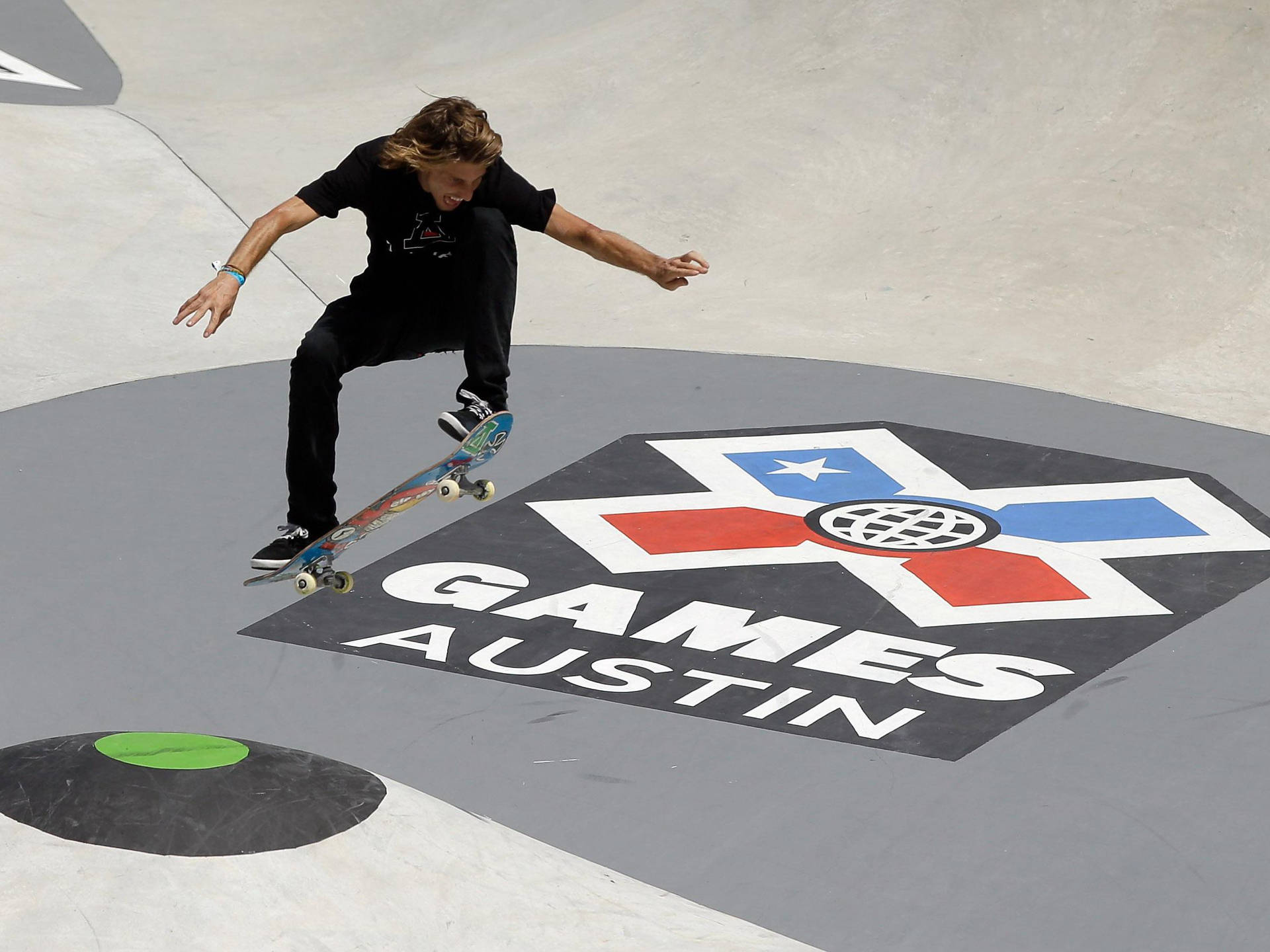 滑板手在混凝土坡道上的X Games Austin標誌上方表演技巧。