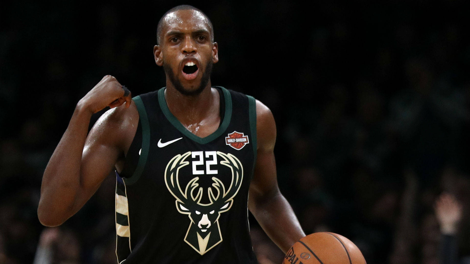 職業球員 Khris Middleton 壁紙 — 一名身穿密爾沃基公鹿隊球衣的籃球運動員，手持籃球並握緊拳頭，發出勝利的怒吼。