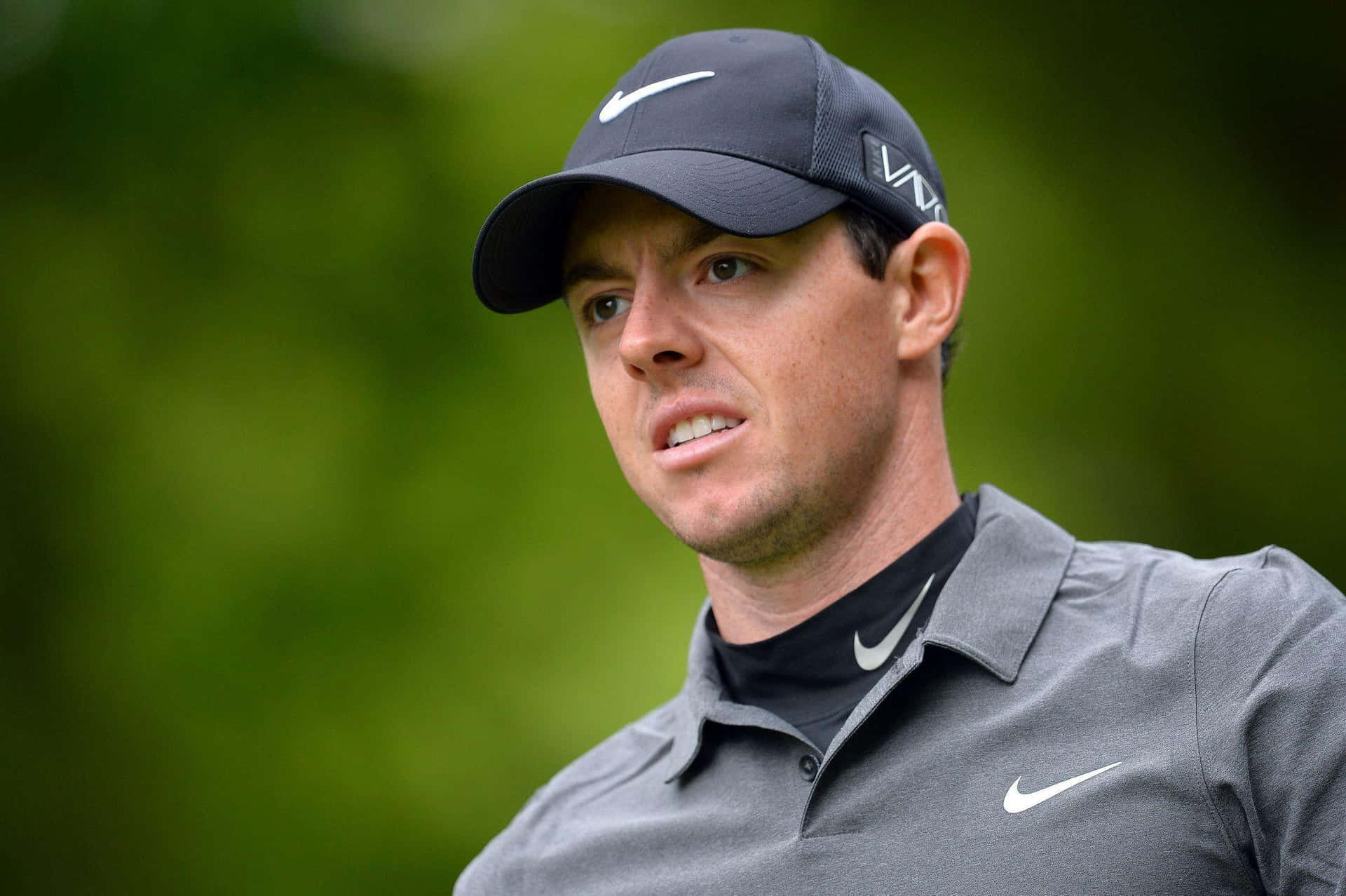 高爾夫球手Rory McIlroy戴著深色帽子和灰色Polo衫在戶外。