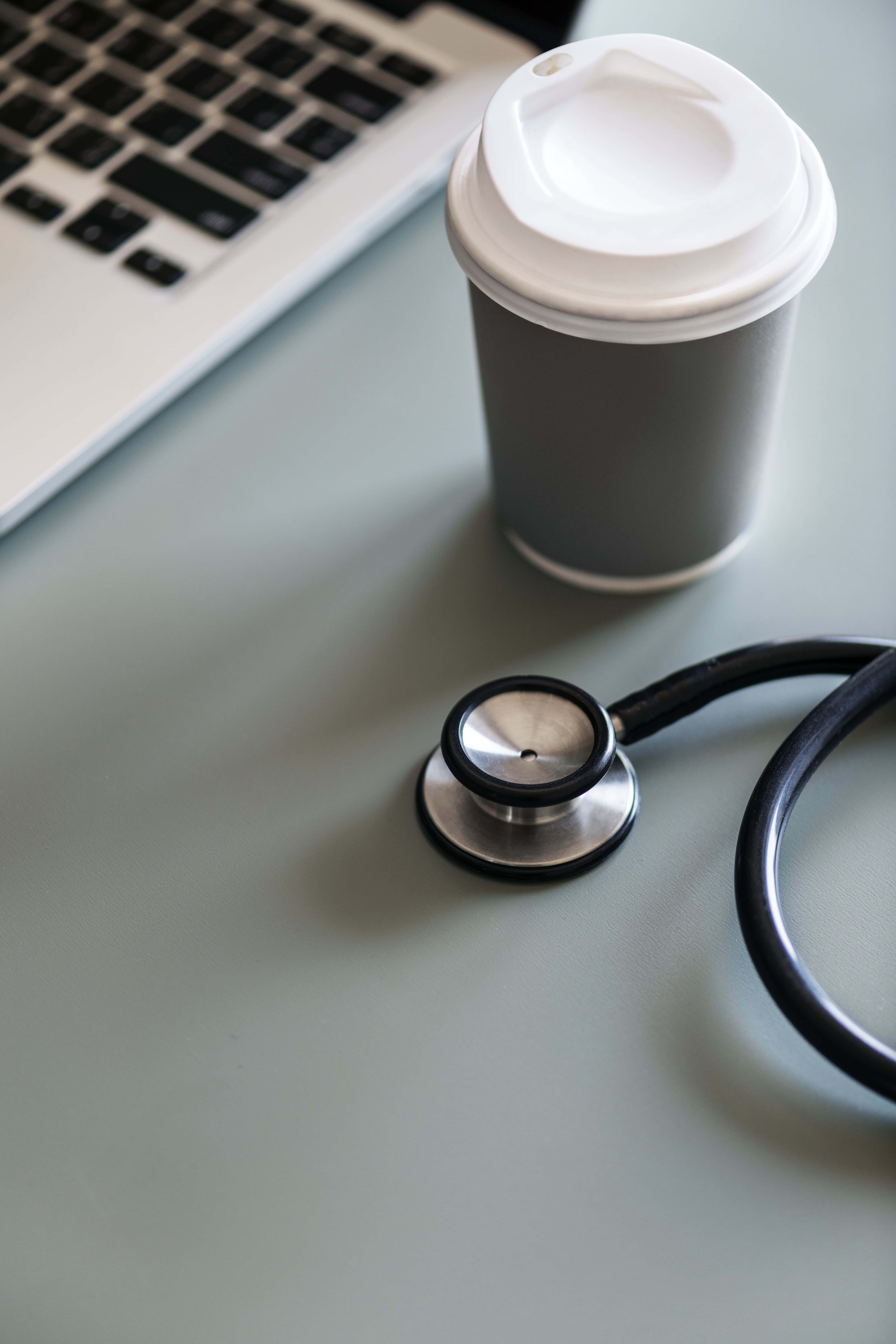 Stethoscope 桌布 壁紙 — 聽診器咖啡杯和手提電腦放在現代工作空間的時尚灰色桌子上。