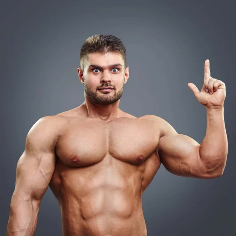 肌肉男指向上方圖片 壁紙 — 一個冇著衫嘅肌肉男，留鬍鬚，喺純灰色背景前，用食指指向上，眼神銳利。
