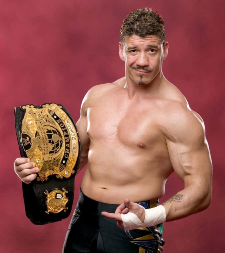WWE 桌布 壁紙 — 肌肉發達嘅摔角手 Eddie Guerrero 自信咁擺甫士，揸住 WWE Intercontinental Championship 腰帶，背景係深紅色嘅攝影棚。