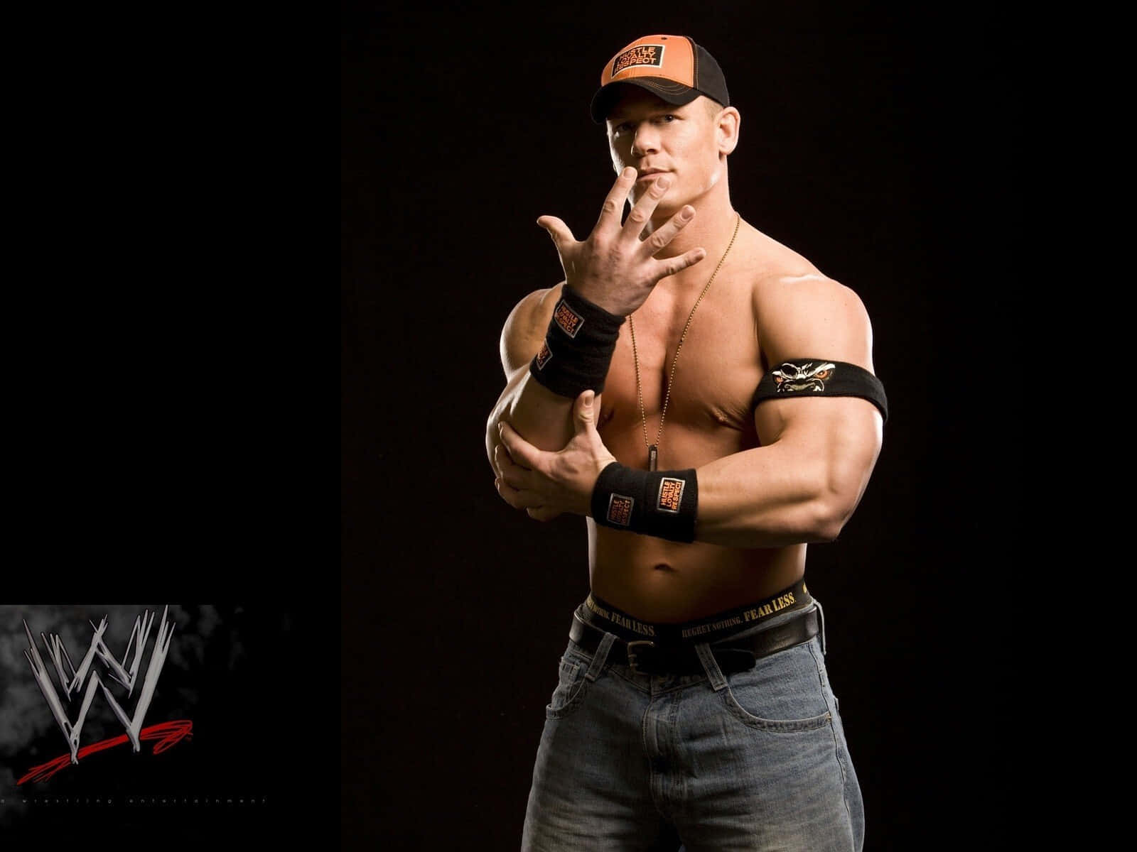 WWE Logo 桌布 壁紙 — 肌肉發達的摔角手約翰·辛納在黑色背景前自信地穿著牛仔褲和帽子擺姿勢，帶有WWE標誌。
