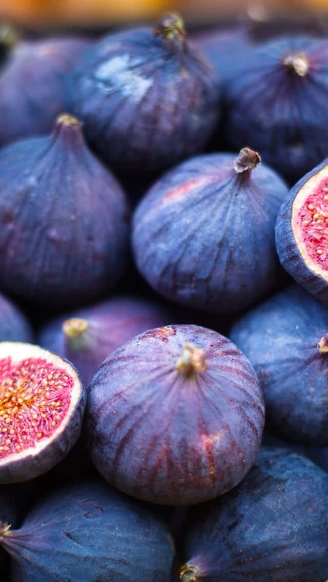 Purple Figs 桌布 壁紙 — 肥美紫色無花果嘅特寫，其中一個切開一半，露出多汁嘅粉紅色果肉同金色種子。