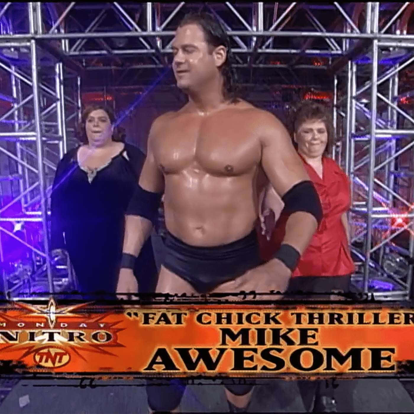 摔角手 Mike Awesome 在擂台上，身後有兩名女子，在舞台燈光下。