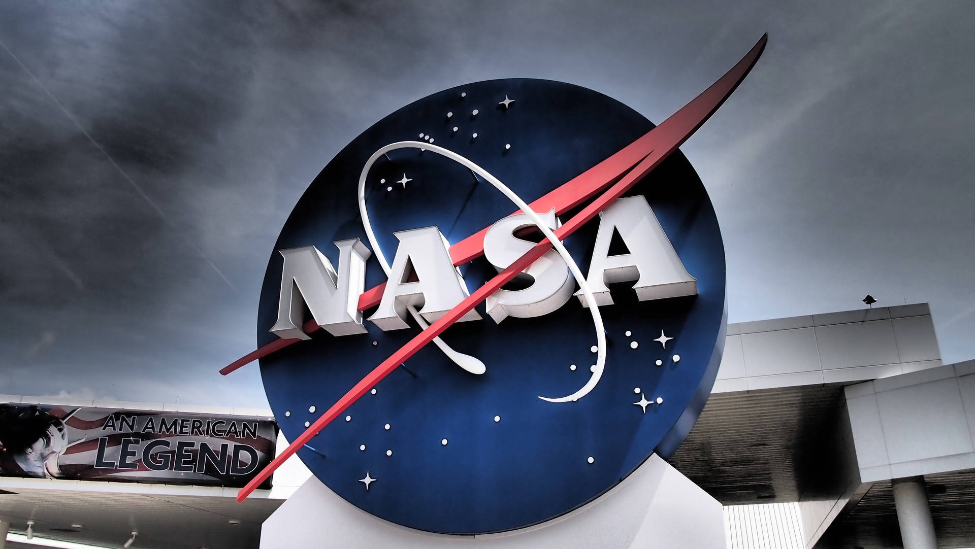 多雲天空下現代建築附近的大型NASA標誌雕塑。 — Nasa GIF 壁紙
