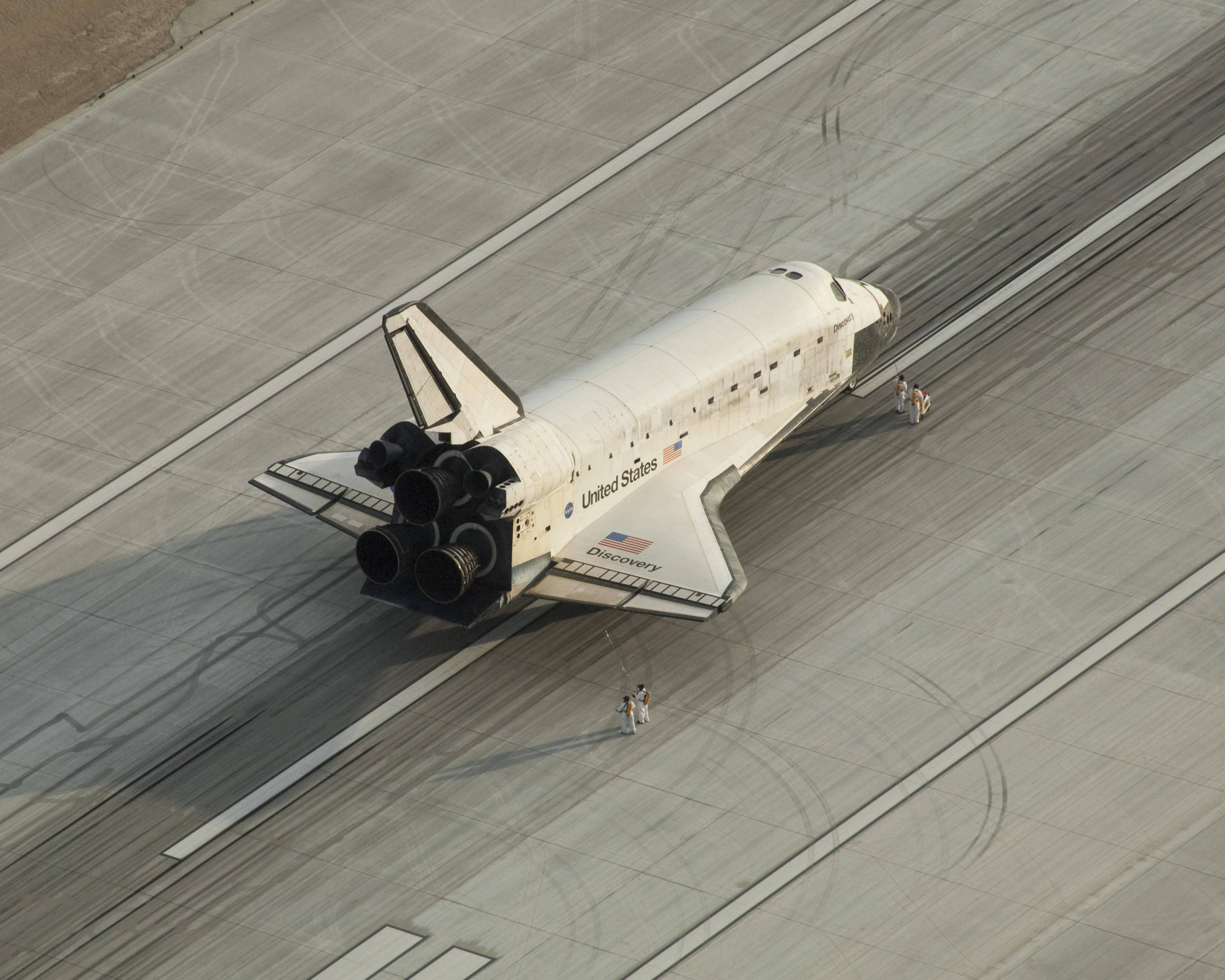 肯尼迪航天中心STS-128太空梭著陸 壁紙 — NASA嘅穿梭機發現號喺混凝土跑道上面嘅航拍圖，附近有細小人物做比例。