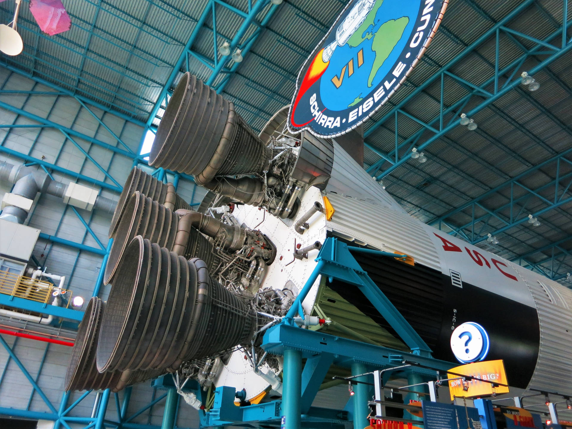 在博物館機庫中展示的大型火箭引擎，帶有藍色結構樑。 — Nasa GIF 壁紙