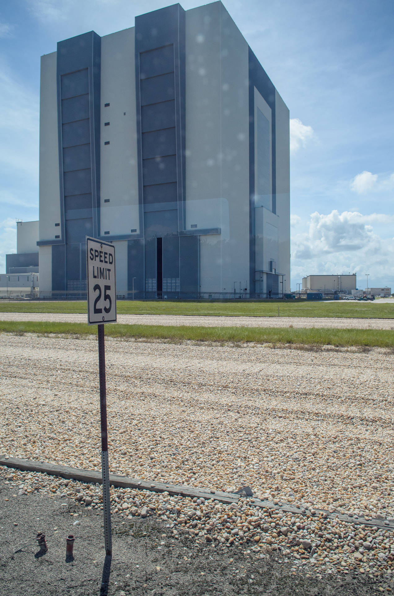 碎石路上火箭發射塔前的速度限制25標誌。 — Nasa GIF 壁紙