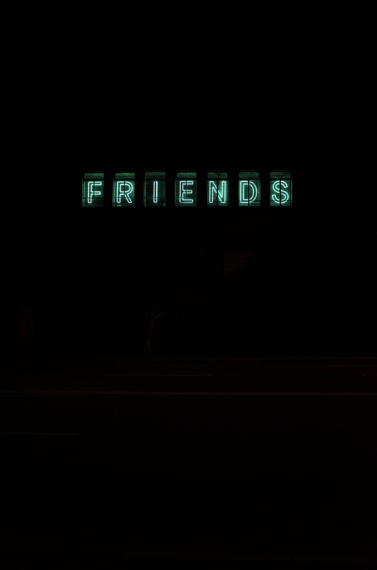 一個發光的綠色霓虹燈牌，在黑暗背景下顯示 FRIENDS。
