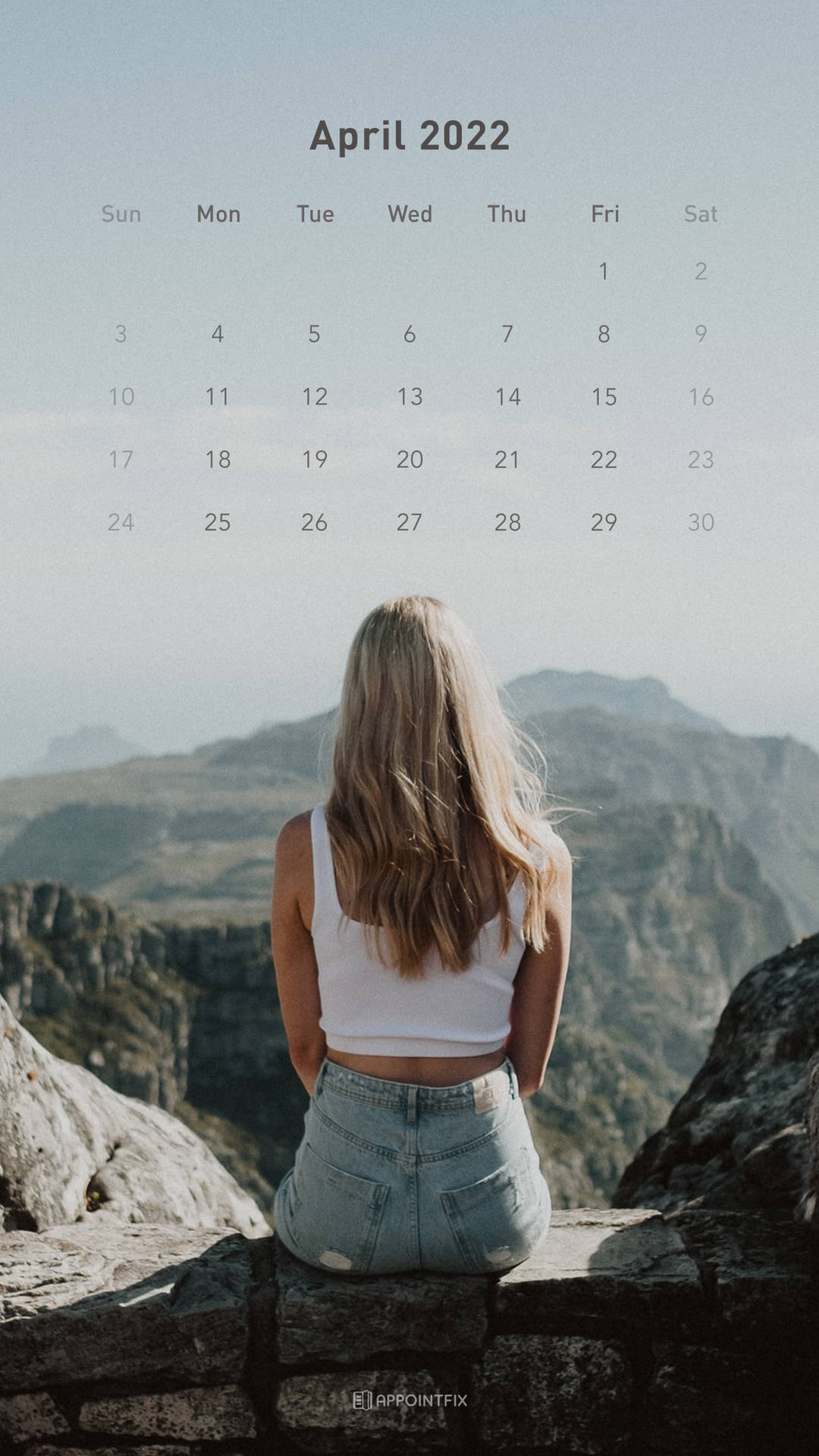 身穿白色上衣和牛仔褲的女性坐在岩石上面對山脈，帶有2022年4月日曆疊加。