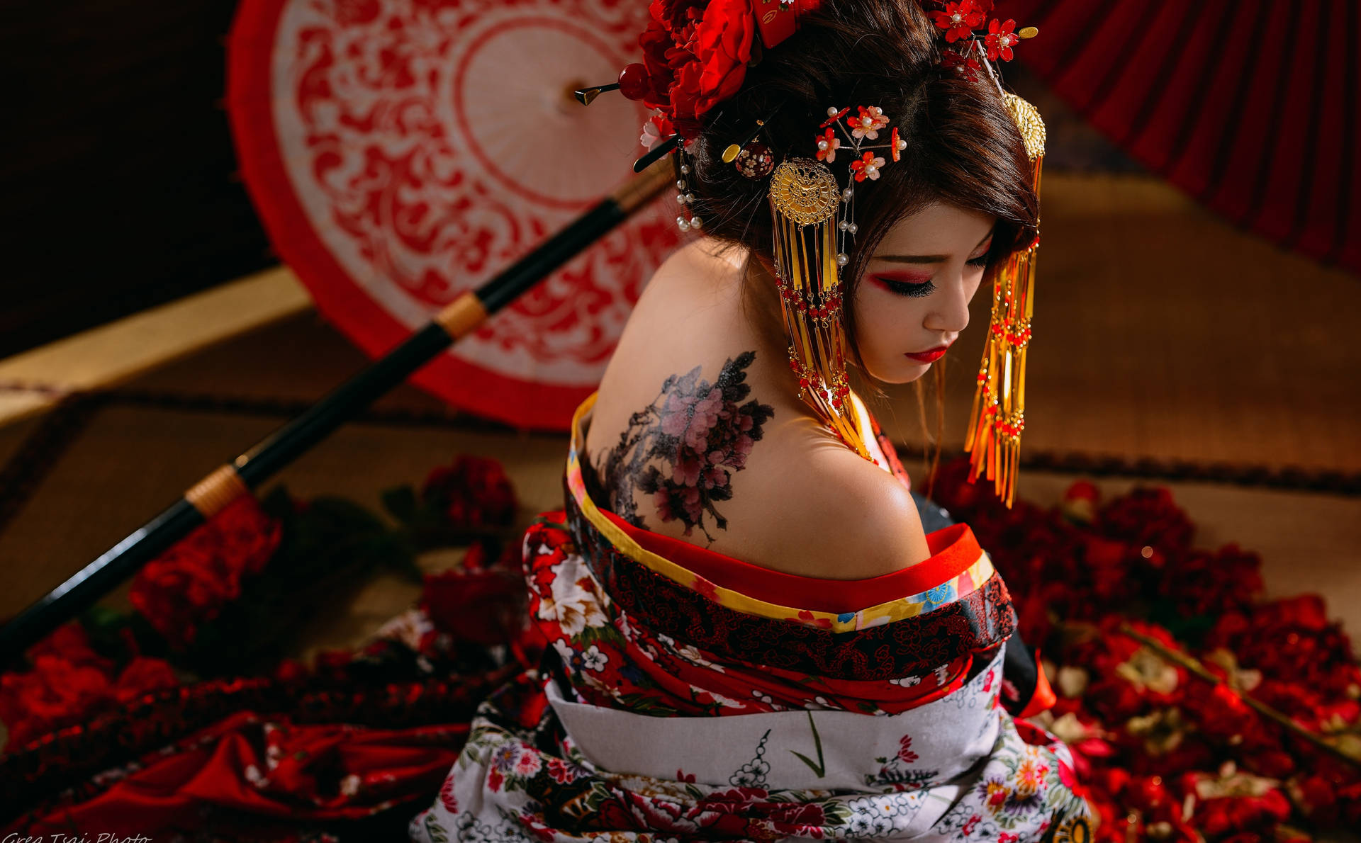 穿著紅白和服、帶有花卉紋身的藝妓，被紅色花瓣包圍。