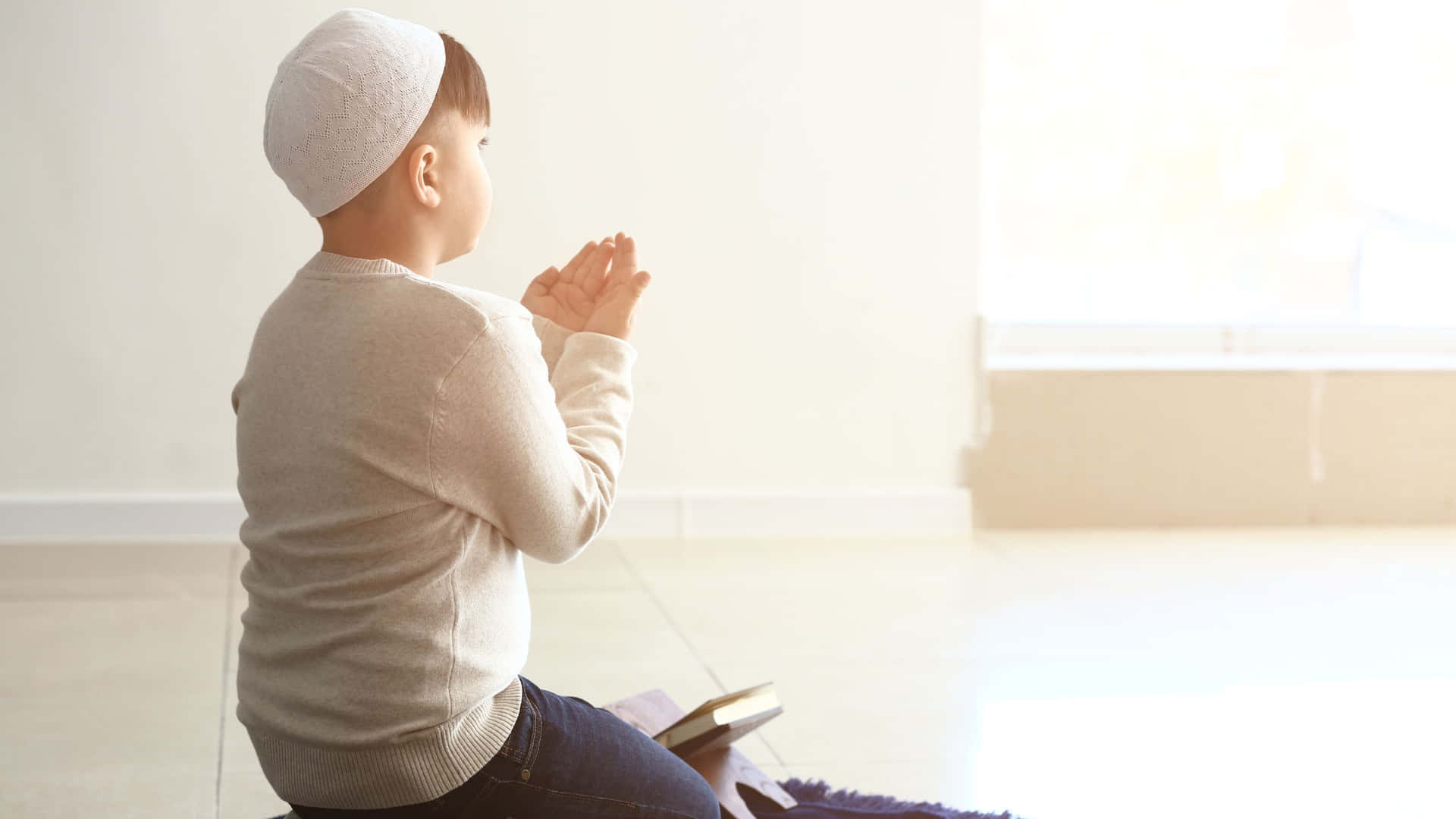小男孩在室內雙手合十祈禱，陽光從窗戶照進來。