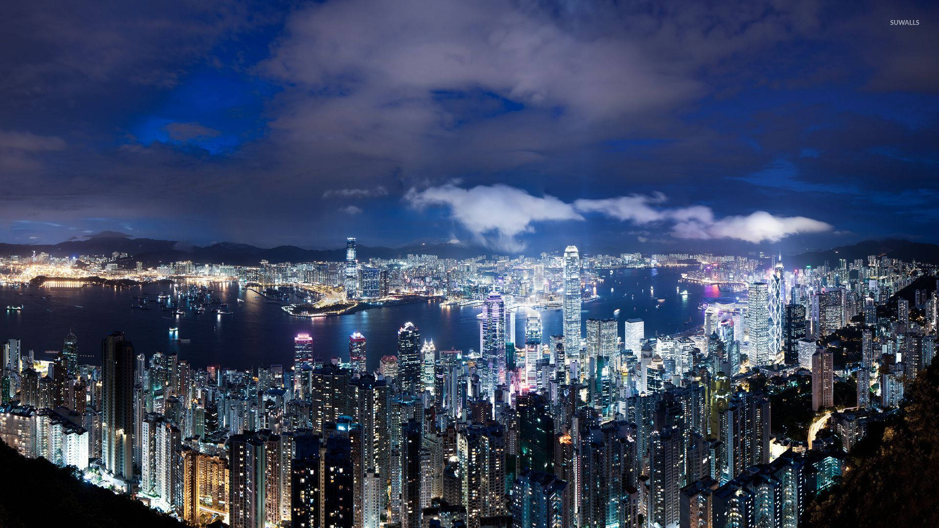 胡志明市夜空 壁紙 — 香港令人驚嘆的夜景，閃爍的摩天大樓和港口在戲劇性的多雲天空下。