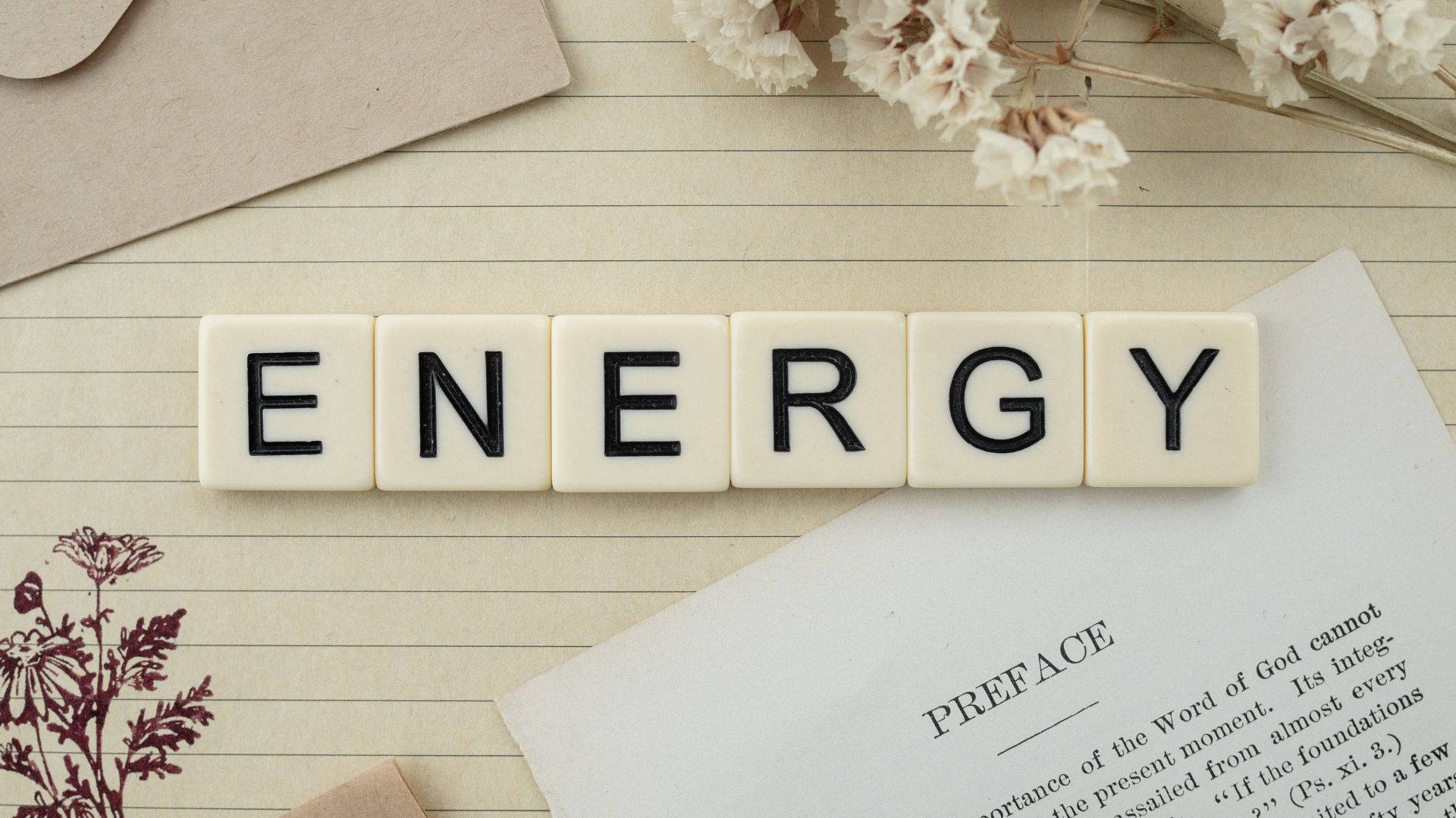 奶油色瓷磚在橫線紙上拼出ENERGY，配有乾花和書頁。