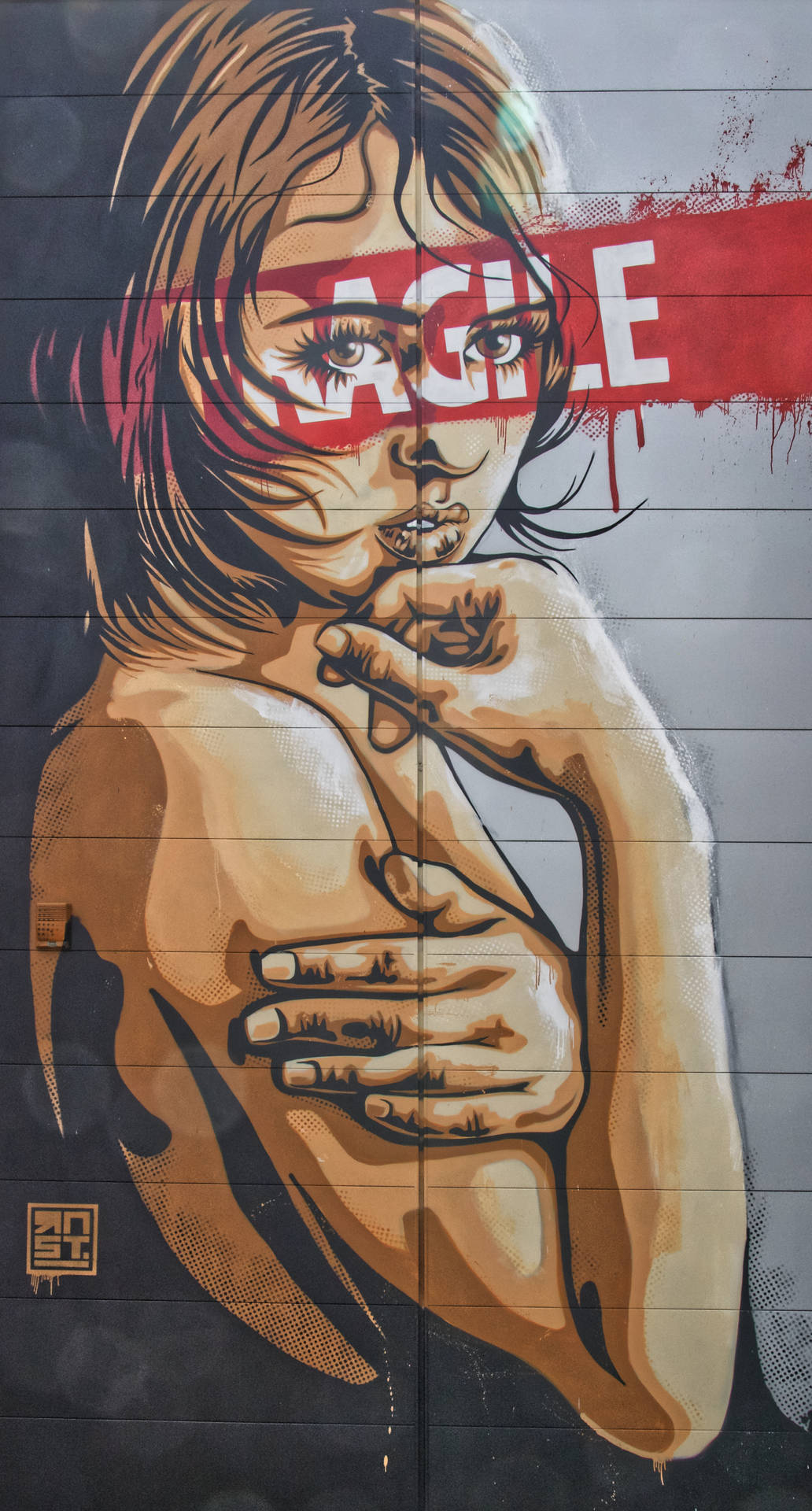 塗鴉壁畫，女性眼睛上有「FRAGILE」，手放在肩膀上。