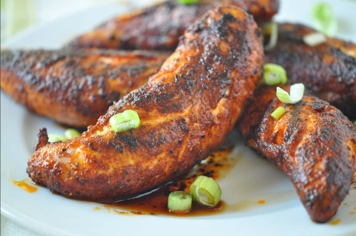 Blackened Chicken 桌布 壁紙 — 脆烤雞柳，配上濃郁醬汁，並以新鮮青蔥點綴，盛載於白色碟上。