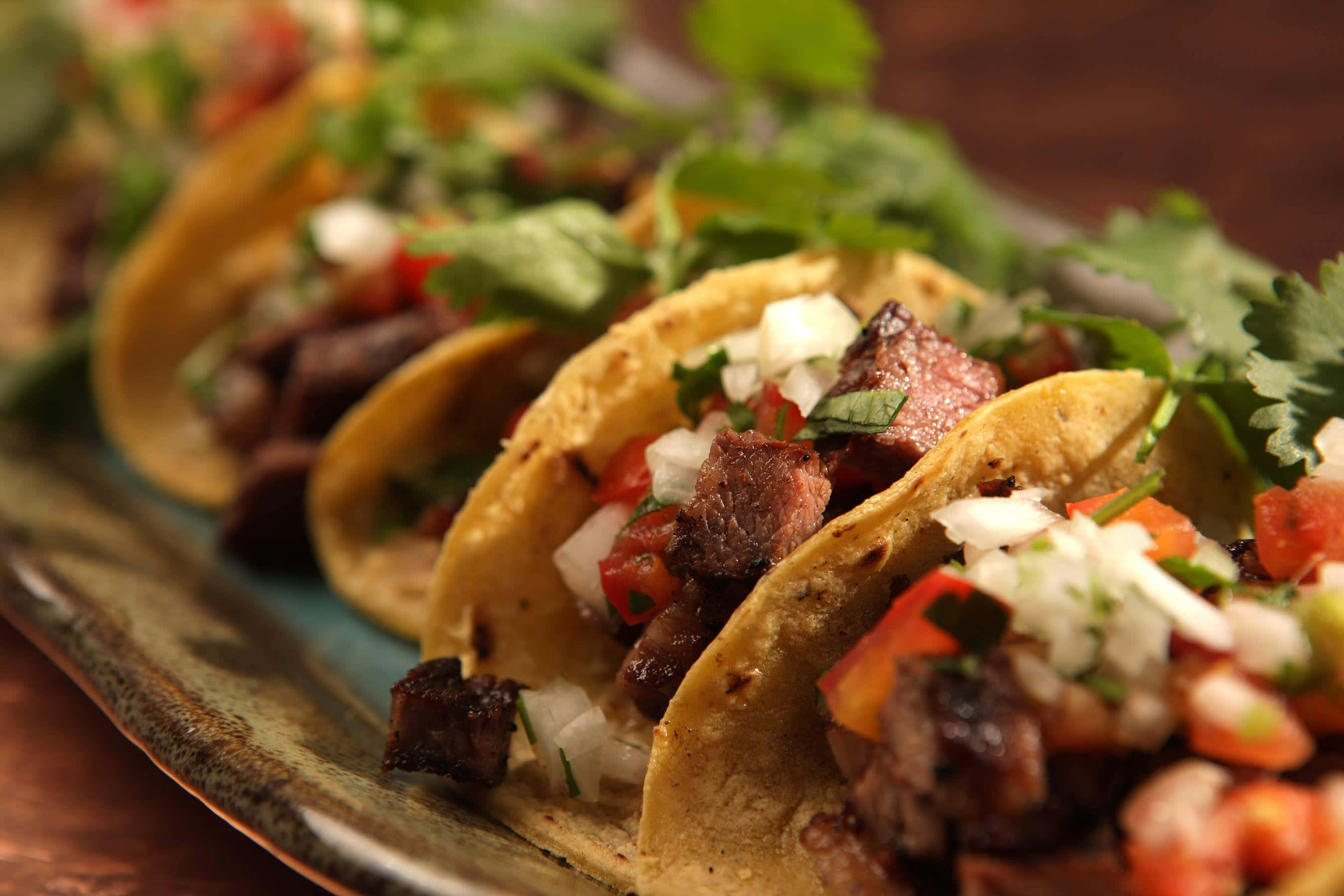 Taco 桌布 壁紙 — 脆玉米餅塔可的近距離特寫，內餡有美味的烤牛肉、新鮮的墨西哥番茄莎莎醬和香菜，放在質樸的陶瓷盤上。