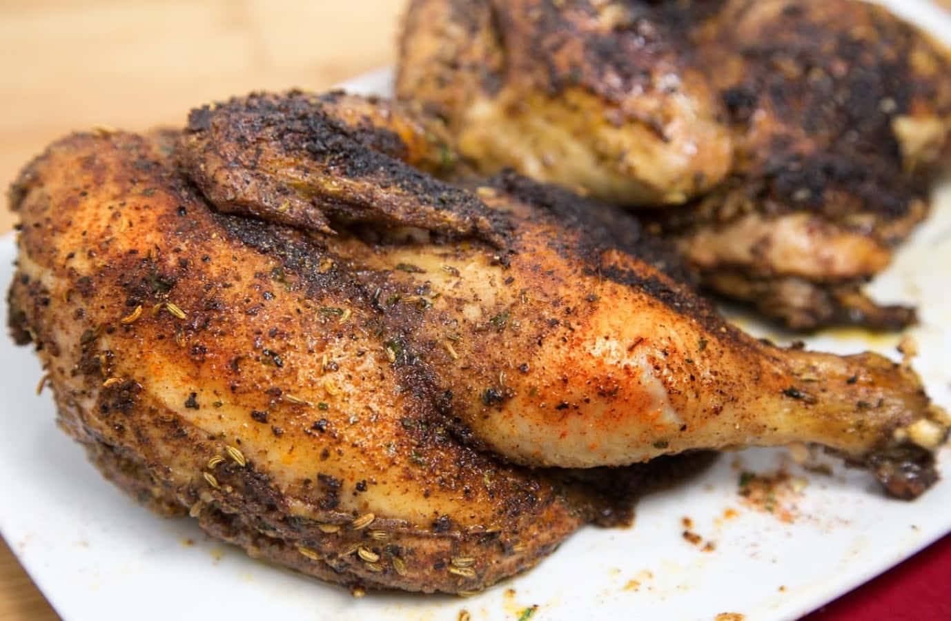 Blackened Chicken 桌布 壁紙 — 脆皮調味烤雞腿，在白色碟子上閃爍著香料光澤。