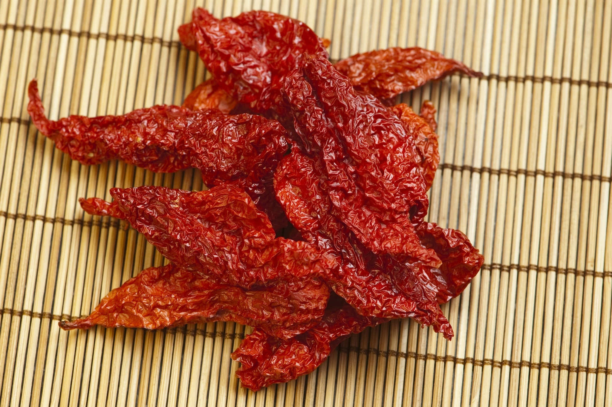 Ghost Pepper 桌布 壁紙 — 脆身乾紅辣椒帶有皺紋質感，放在淺色竹蓆上。
