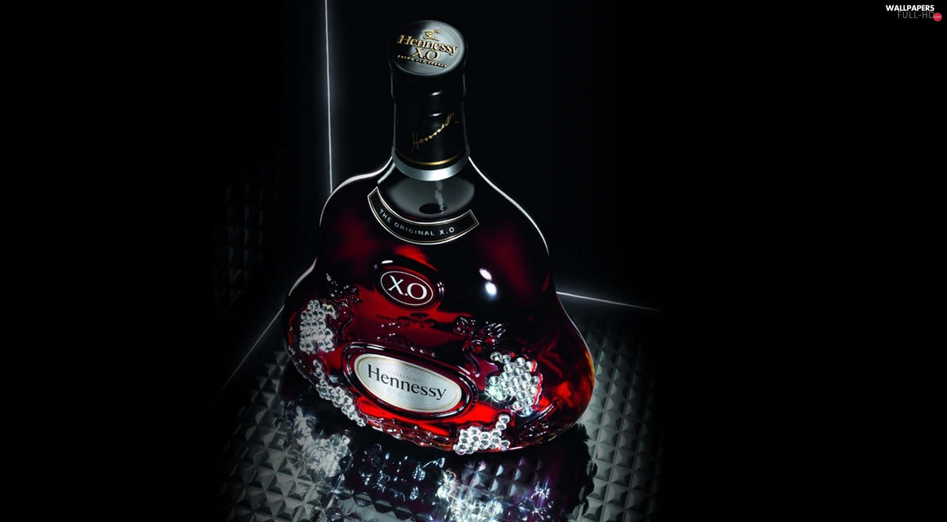 自1765年以來，持續參與生活 壁紙 — 一瓶奢華的Hennessy XO在黑色背景的戲劇性聚光燈下，鑲嵌的水晶閃閃發光。