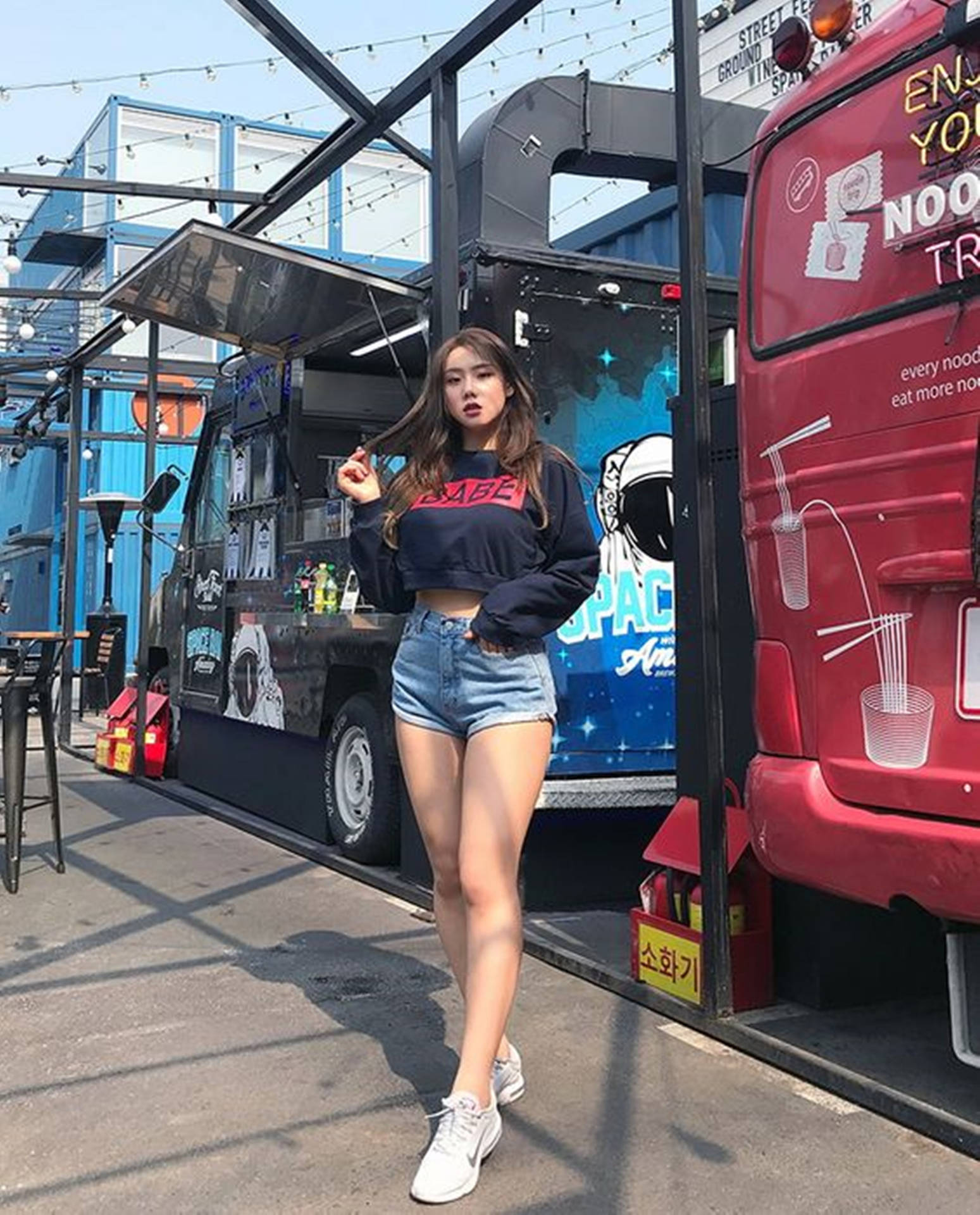 年輕女性在陽光明媚的城市環境中在餐車附近擺姿勢。