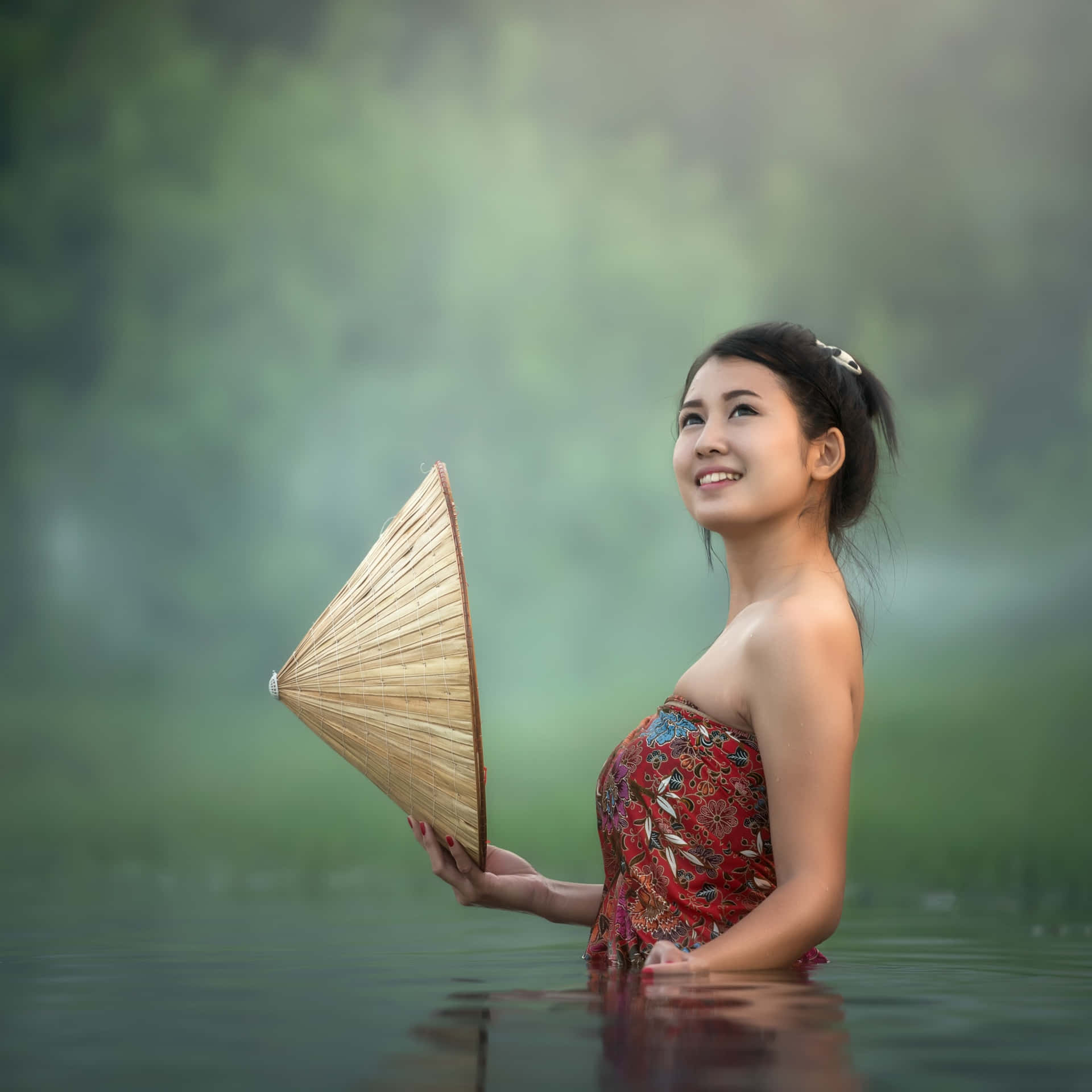 紅裙女子手持竹扇站在霧水中。