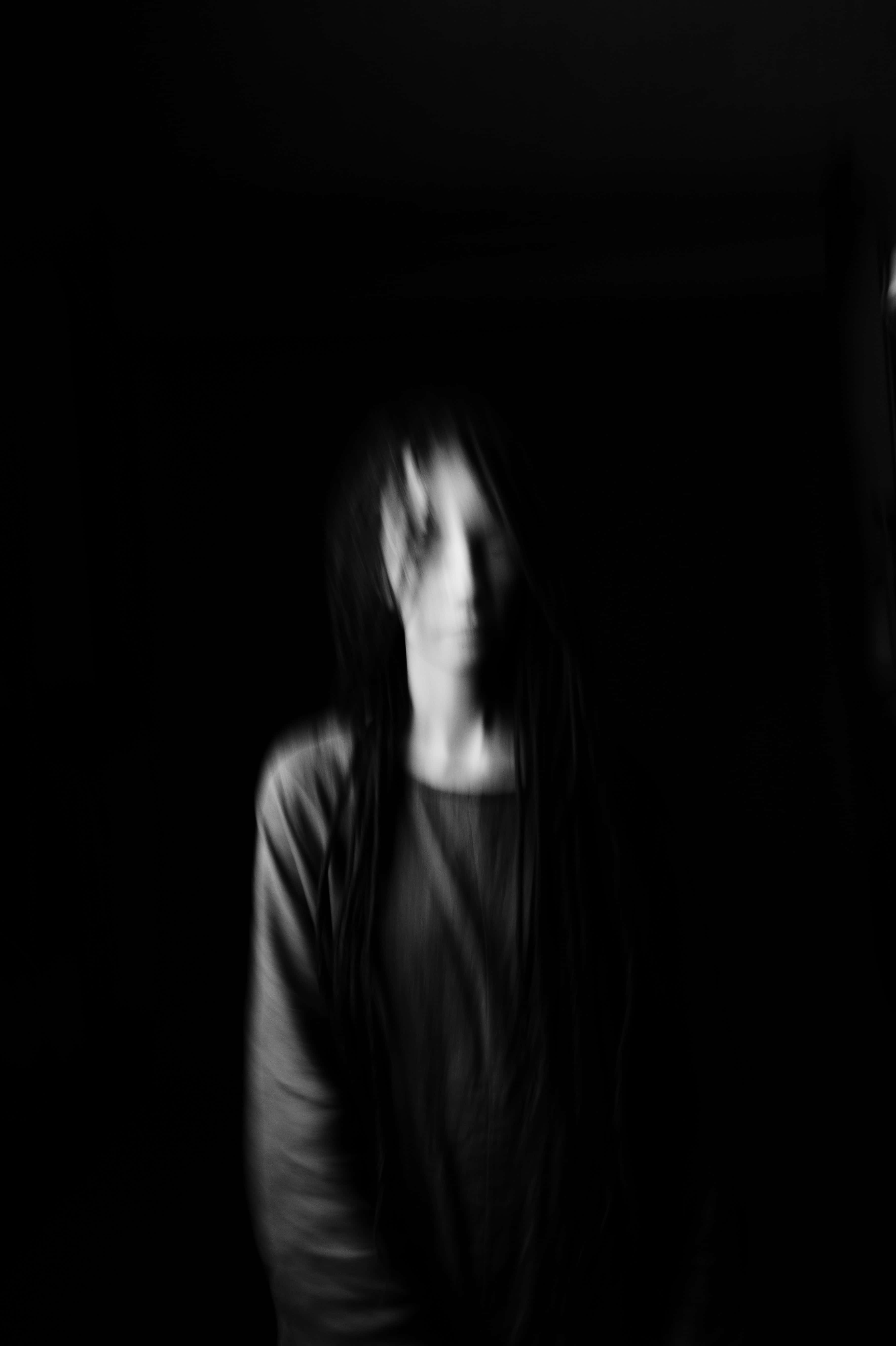 自信黑人女性的美學肖像 壁紙 — 一個模糊的黑白肖像，人物長髮，站在近乎黑暗的環境中，臉上帶有微弱的光線。