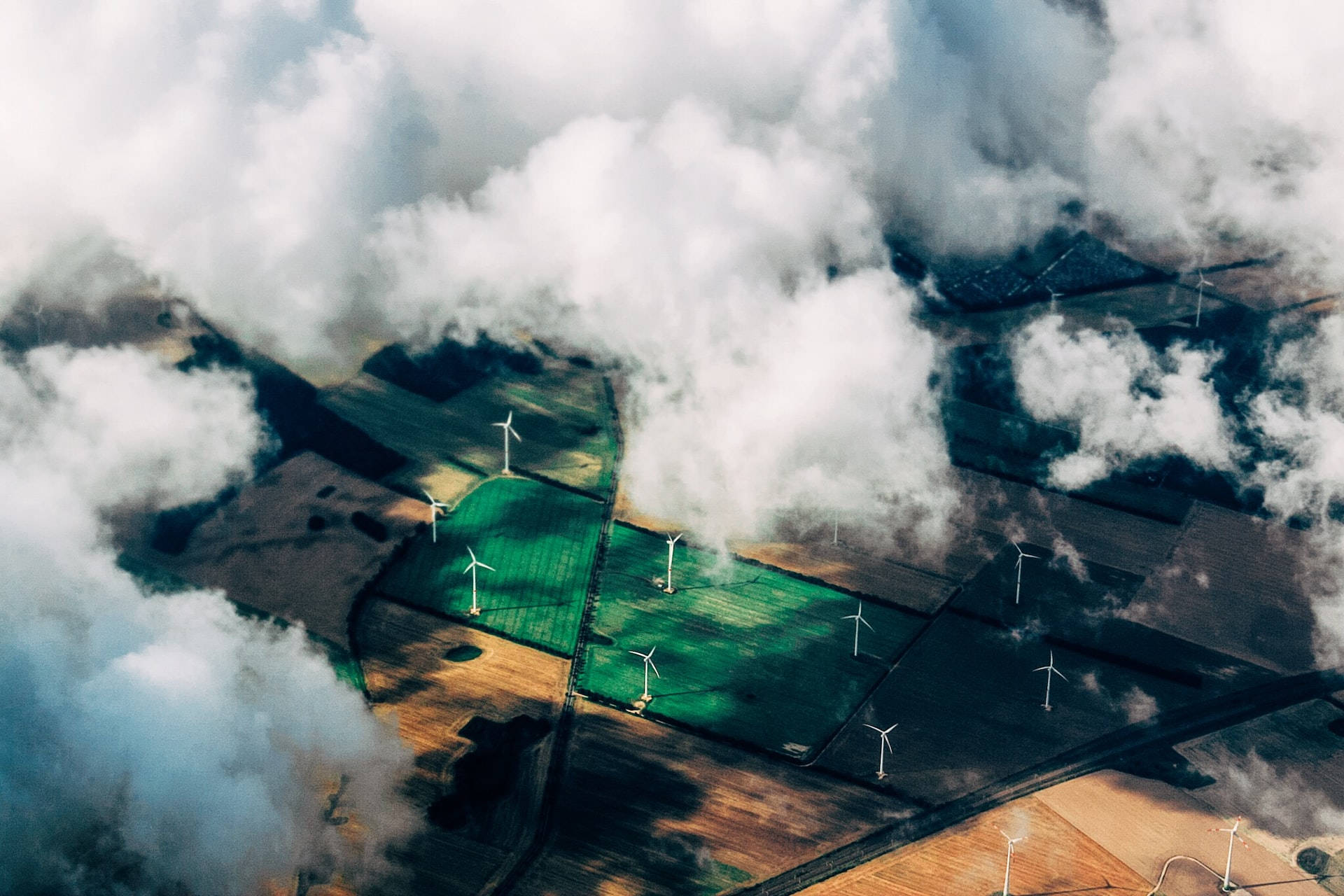 從上方透過雲層看到日落時農田上的風力發電機。