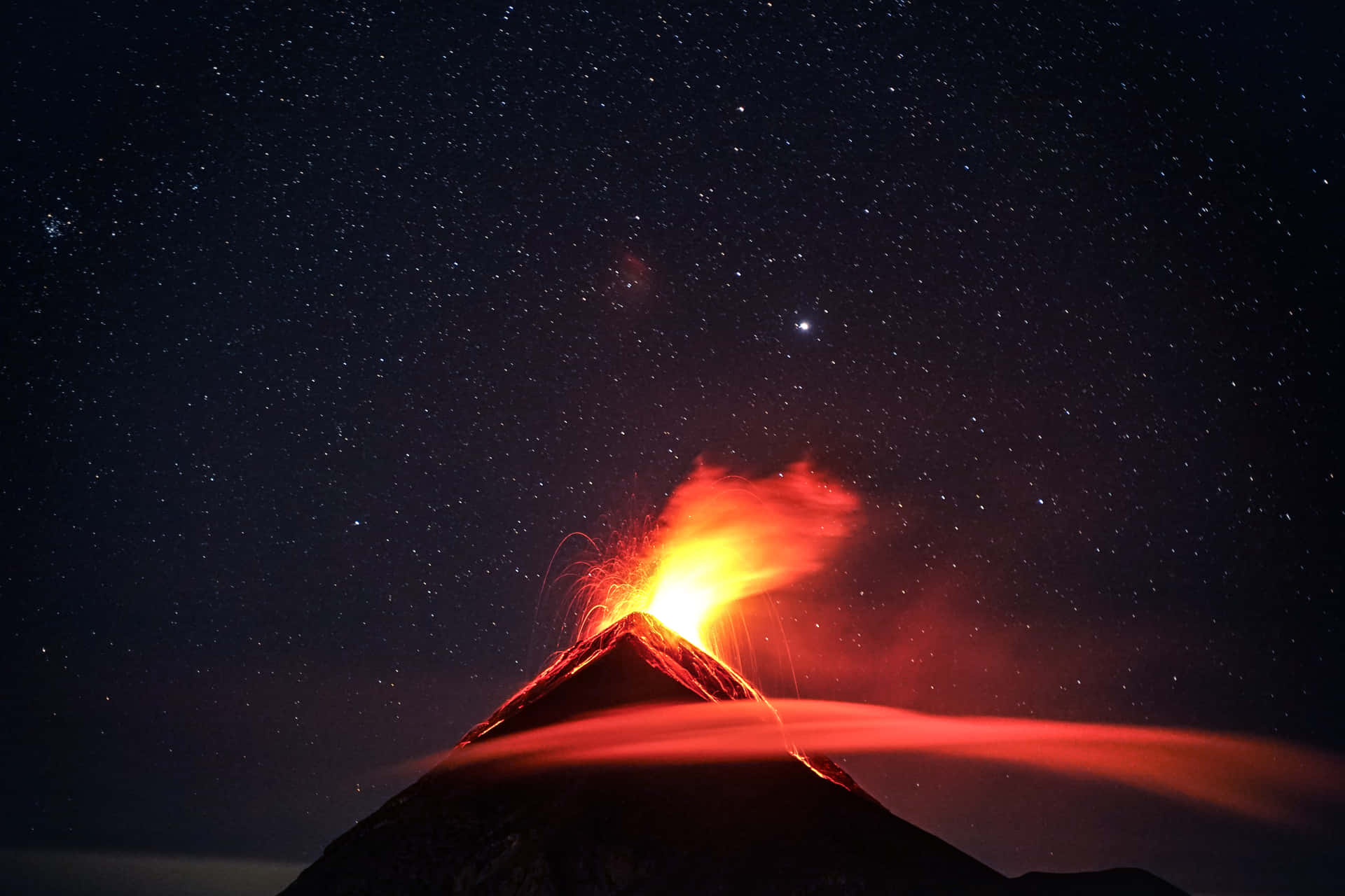 星空下，夜晚噴發的火山，伴隨著熾熱的熔岩和發光的灰燼。