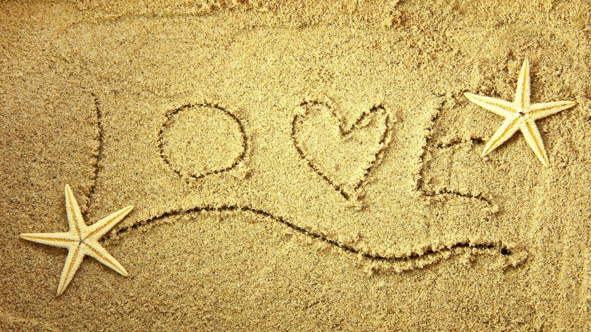 沙中畫出的 love 字樣，旁邊有兩條海星。