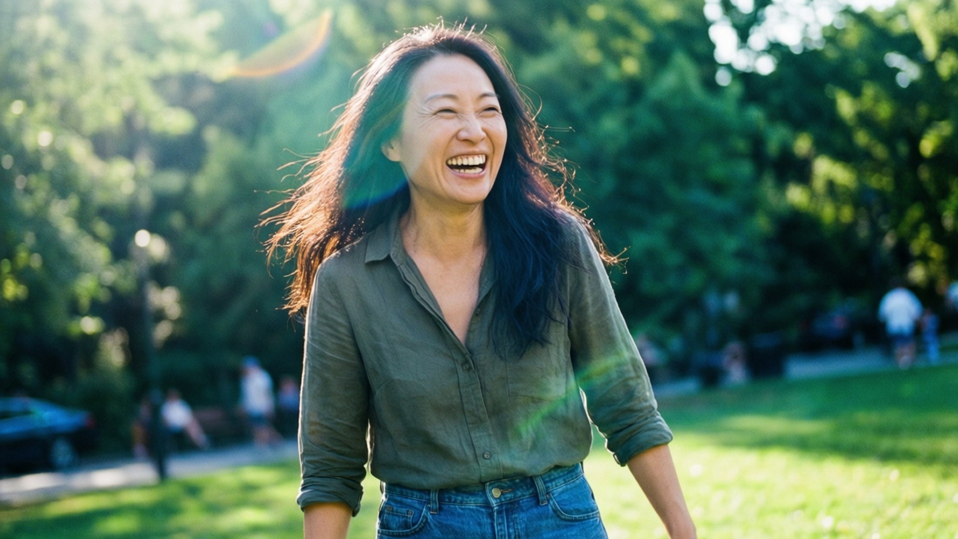 一個女人在陽光明媚的公園裡，有綠樹和草地，她開心地笑著。
