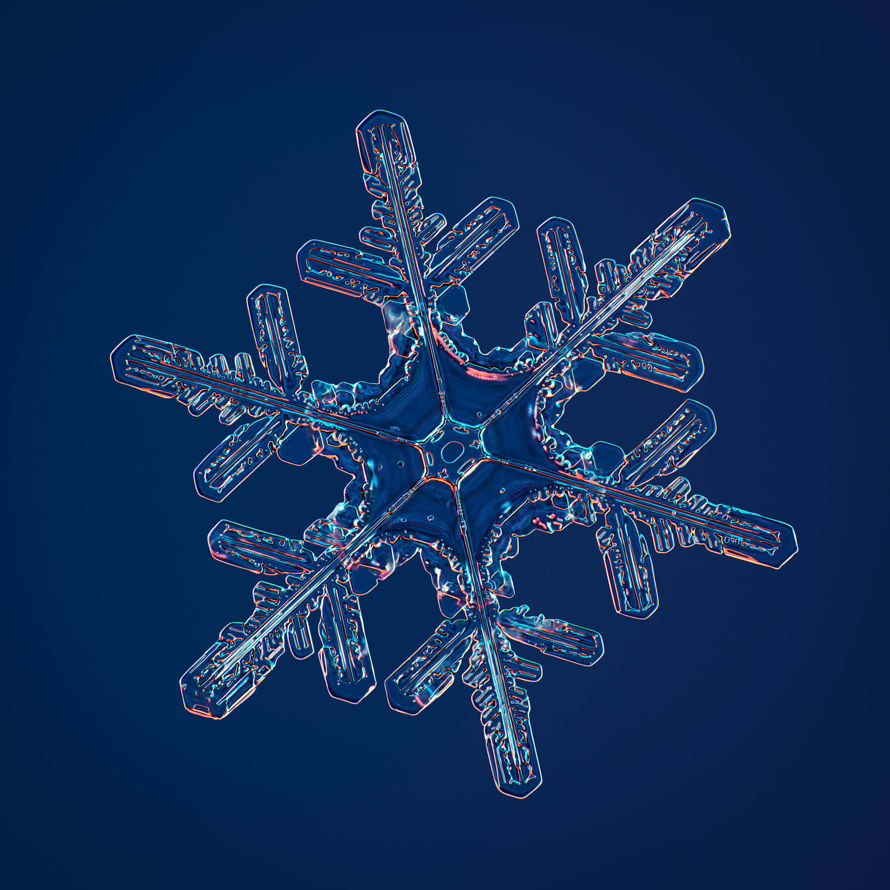 自然的力量：雪花在光線中閃耀 壁紙 — 一片精緻的雪花，帶有發光的藍色和橙色邊緣，漂浮在深藍色背景上。