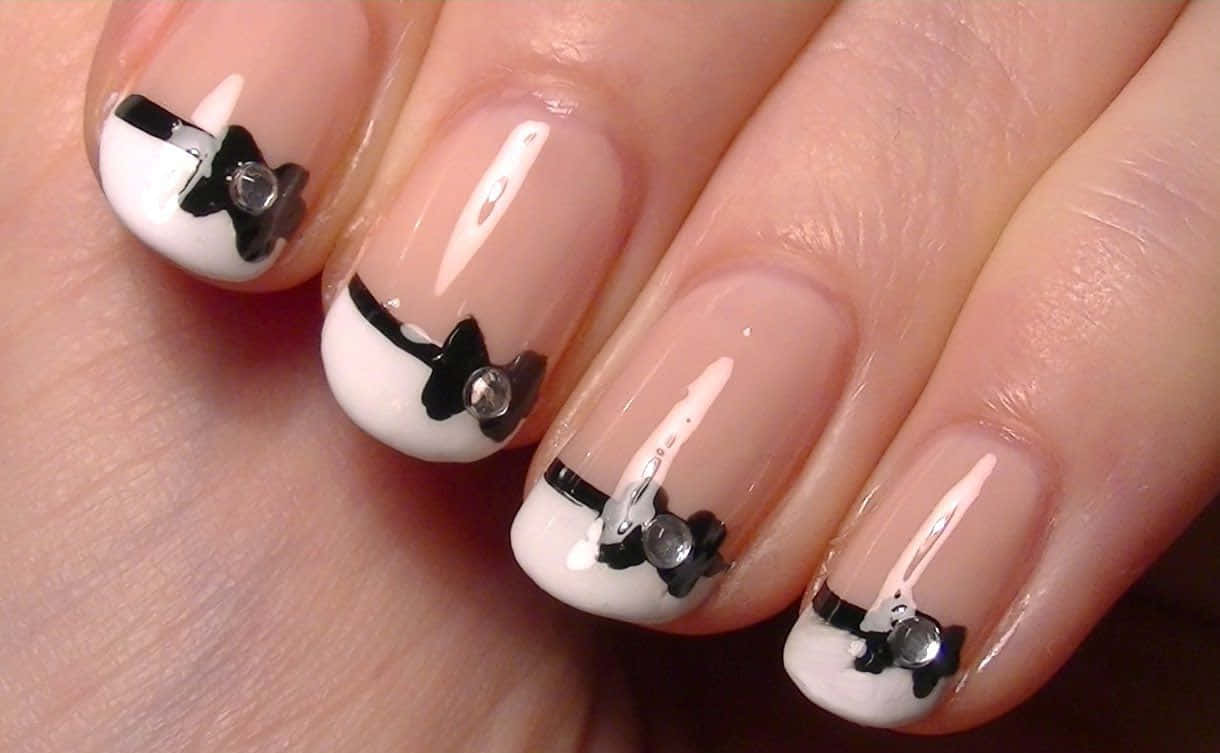 Cute Nails 桌布 壁紙 — 自然肌膚上，白色指尖帶有黑色蝴蝶結和水鑽裝飾的優雅美甲特寫。