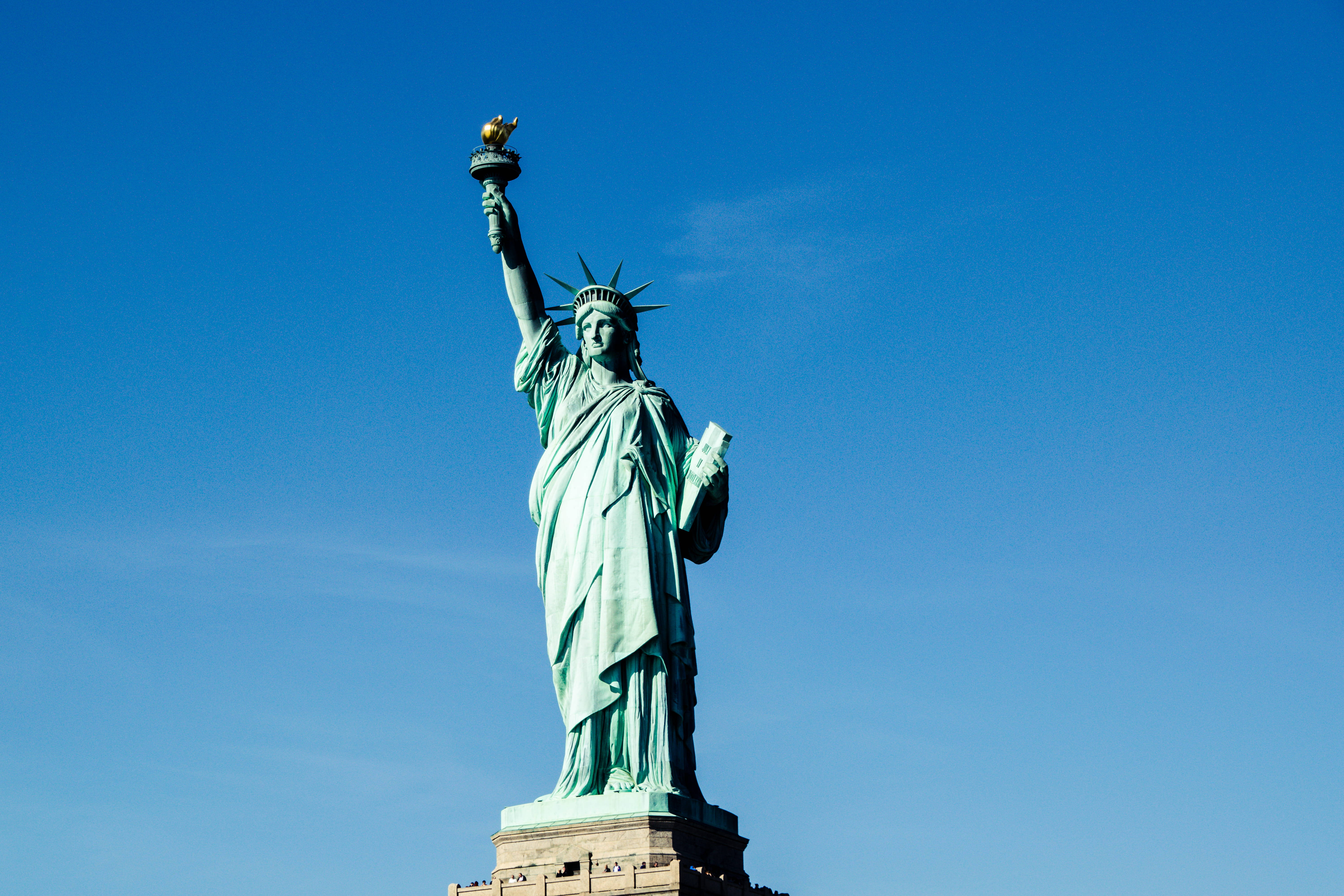 New York 桌布 壁紙 — 自由女神像高聳入雲，在清澈的藍天下高舉火炬，低持石板。