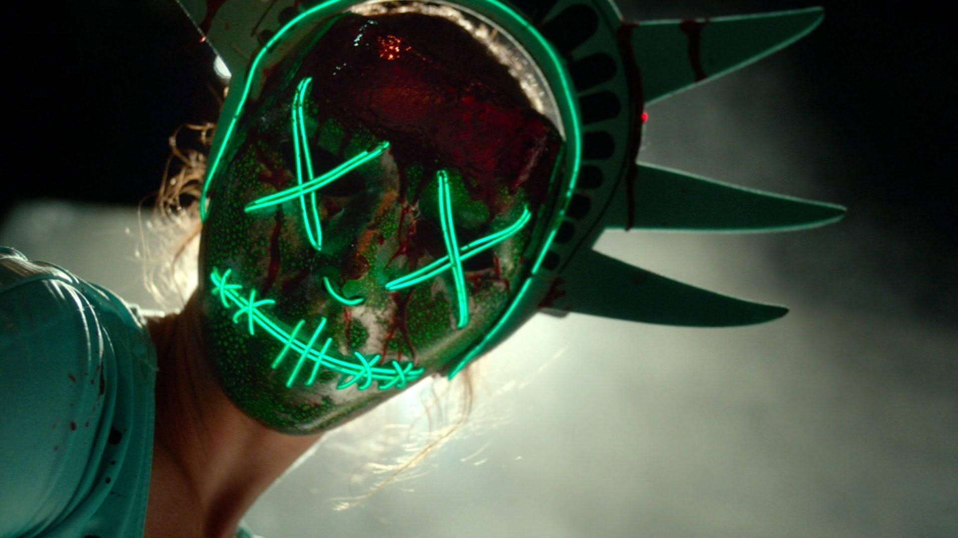 戴著發光綠色自由女神像面具的人，帶有血跡和縫線。