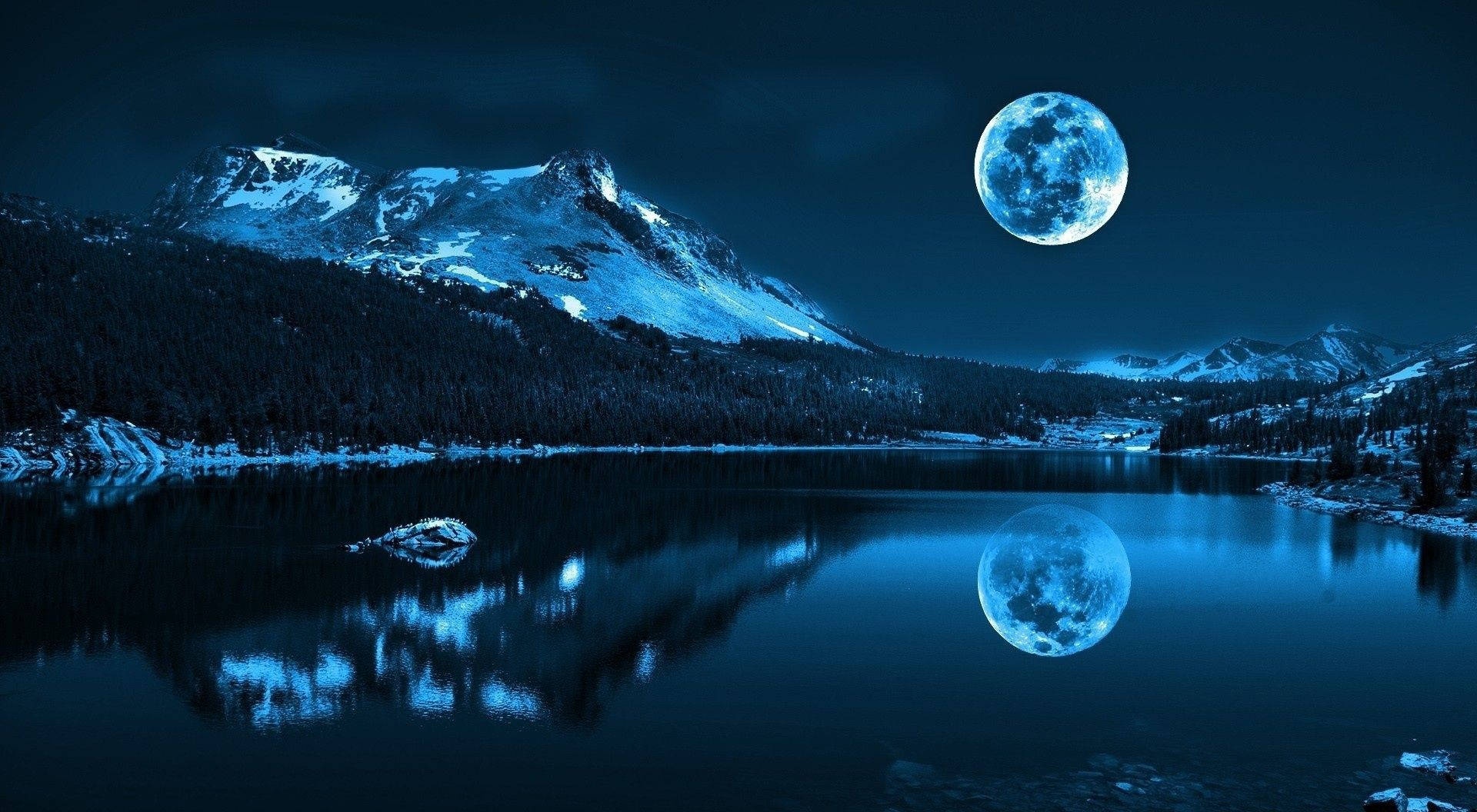 積雪山脈和湖泊在夜間發光的月亮下