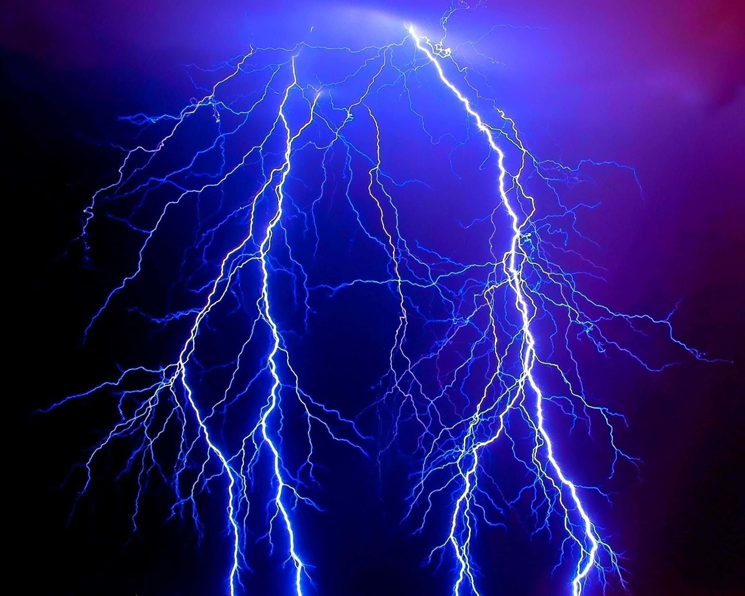 自發光芒的閃電 壁紙 — 一道戲劇性的電藍色閃電在黑暗的天空中叉開，以強烈的能量照亮了旋轉的紫色雲層。