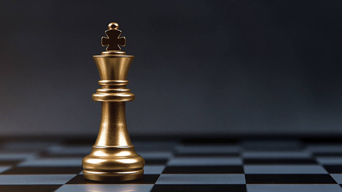 至尊金屬棋王 壁紙 — 一個閃閃發光的金色國際象棋國王高高矗立在棋盤上，背景為深色漸變。
