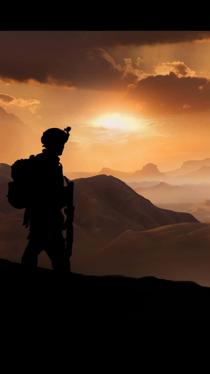 致敬勇敢的印度陸軍 壁紙 — 一名士兵的剪影站在山脊上，夕陽西下，俯瞰層層疊疊沐浴在金色光芒中的山峰。