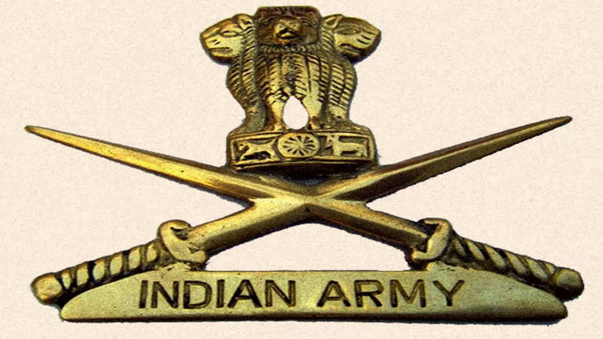 致敬印度陸軍的勇氣與責任 壁紙 — 金色印度陸軍徽章，上有獅子標誌置於交叉劍之上，並附有雕刻文字。