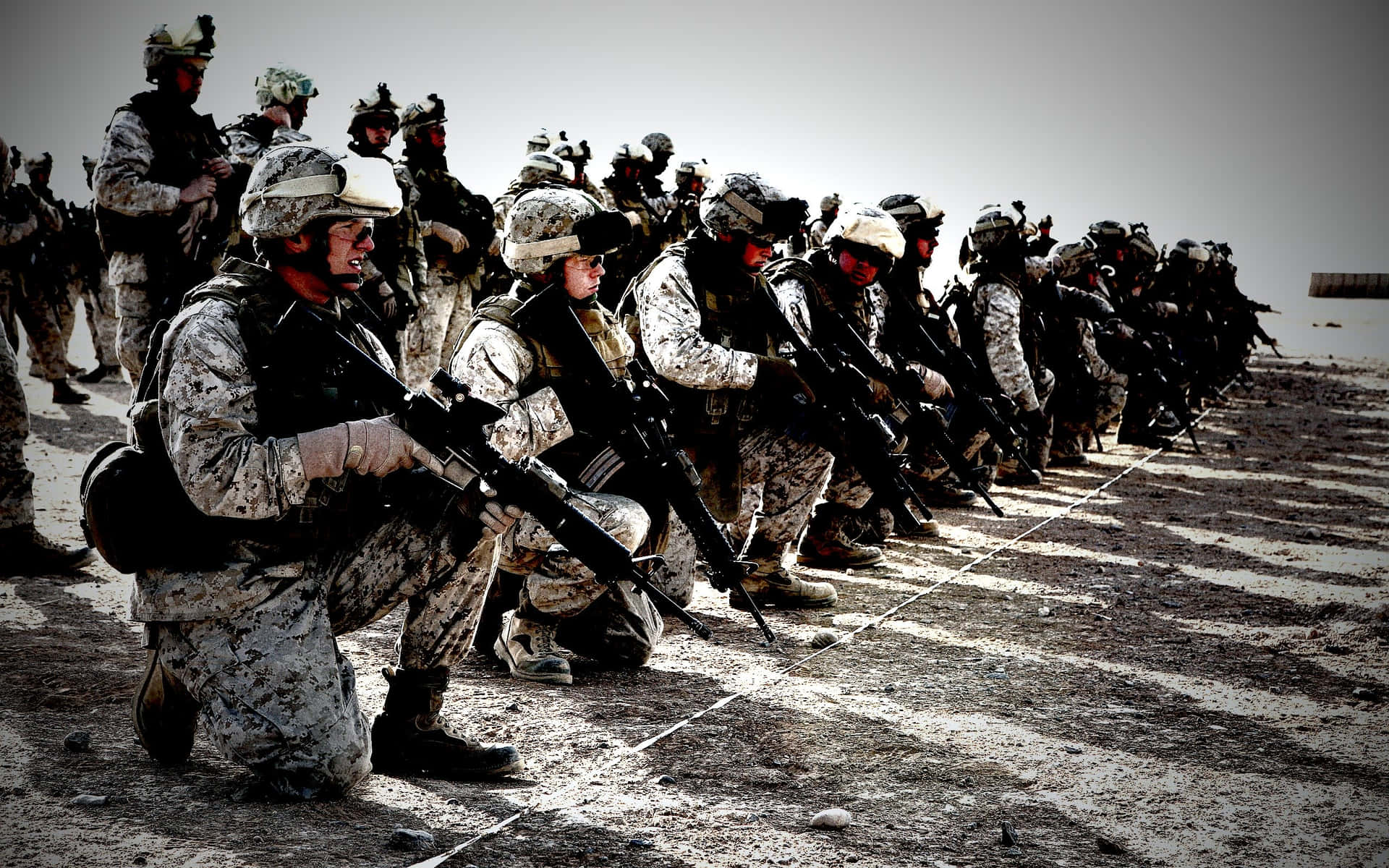 一排身穿沙漠迷彩的武裝士兵跪成隊形。