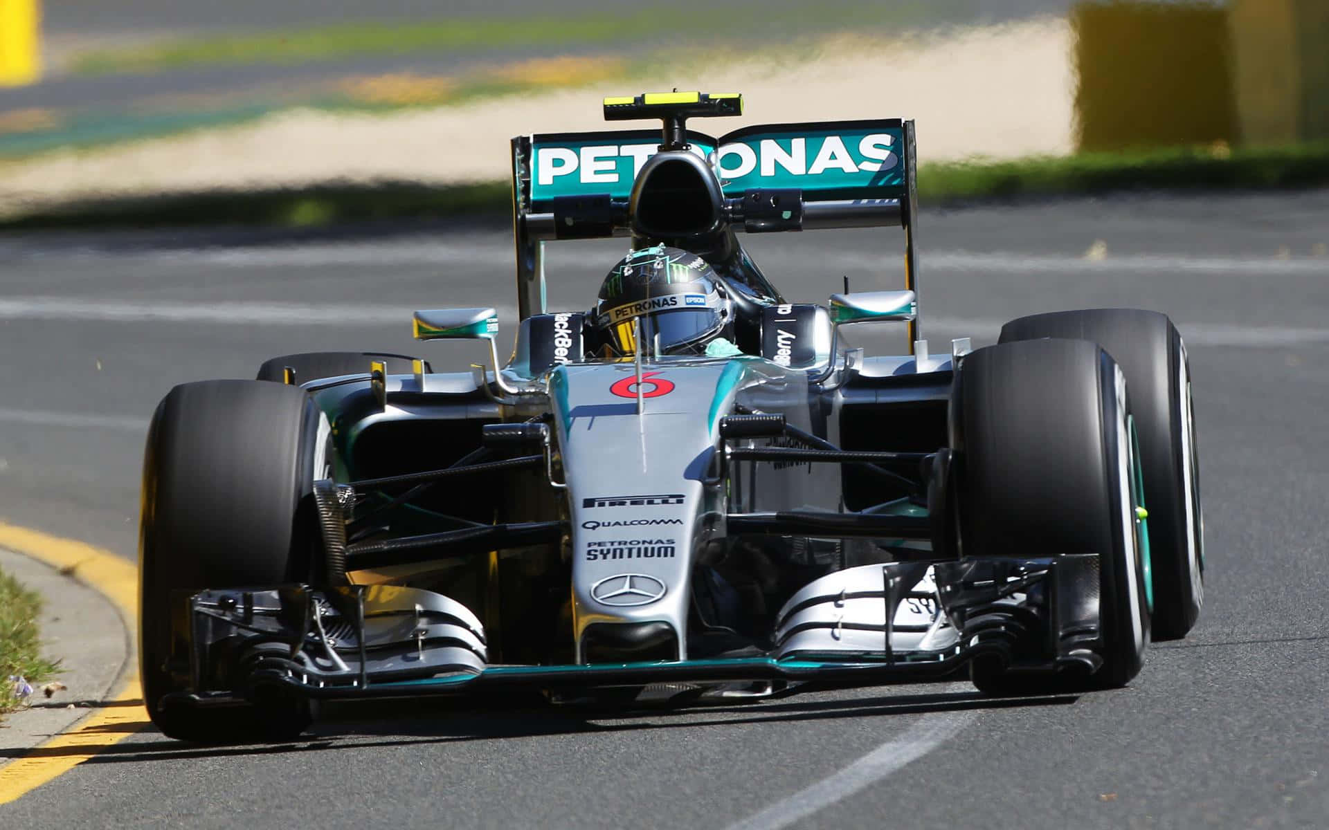 與 F1 2016 一起衝刺！ 壁紙 — 一架銀色和藍綠色的平治一級方程式賽車在賽道彎位高速行駛，車手戴著頭盔清晰可見。
