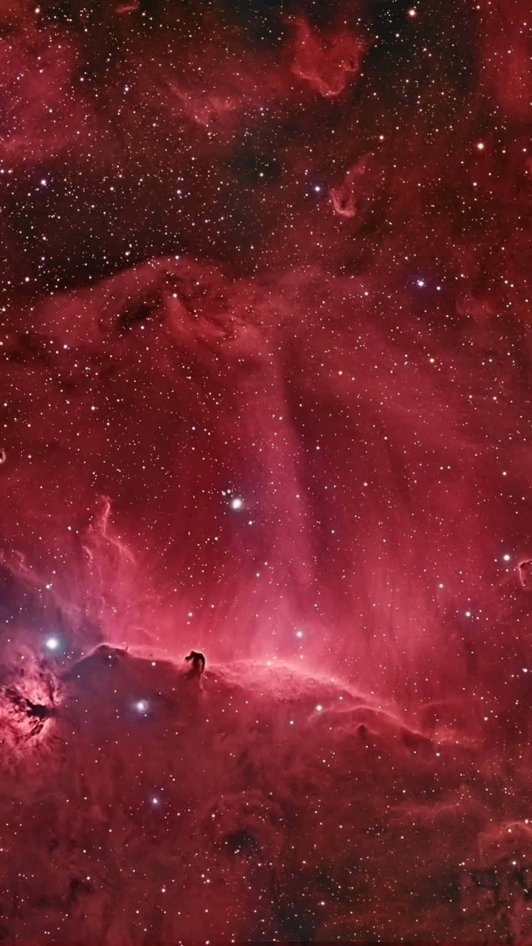 在佈滿星辰的紅色星雲下，宇宙山脊上一個人的剪影。