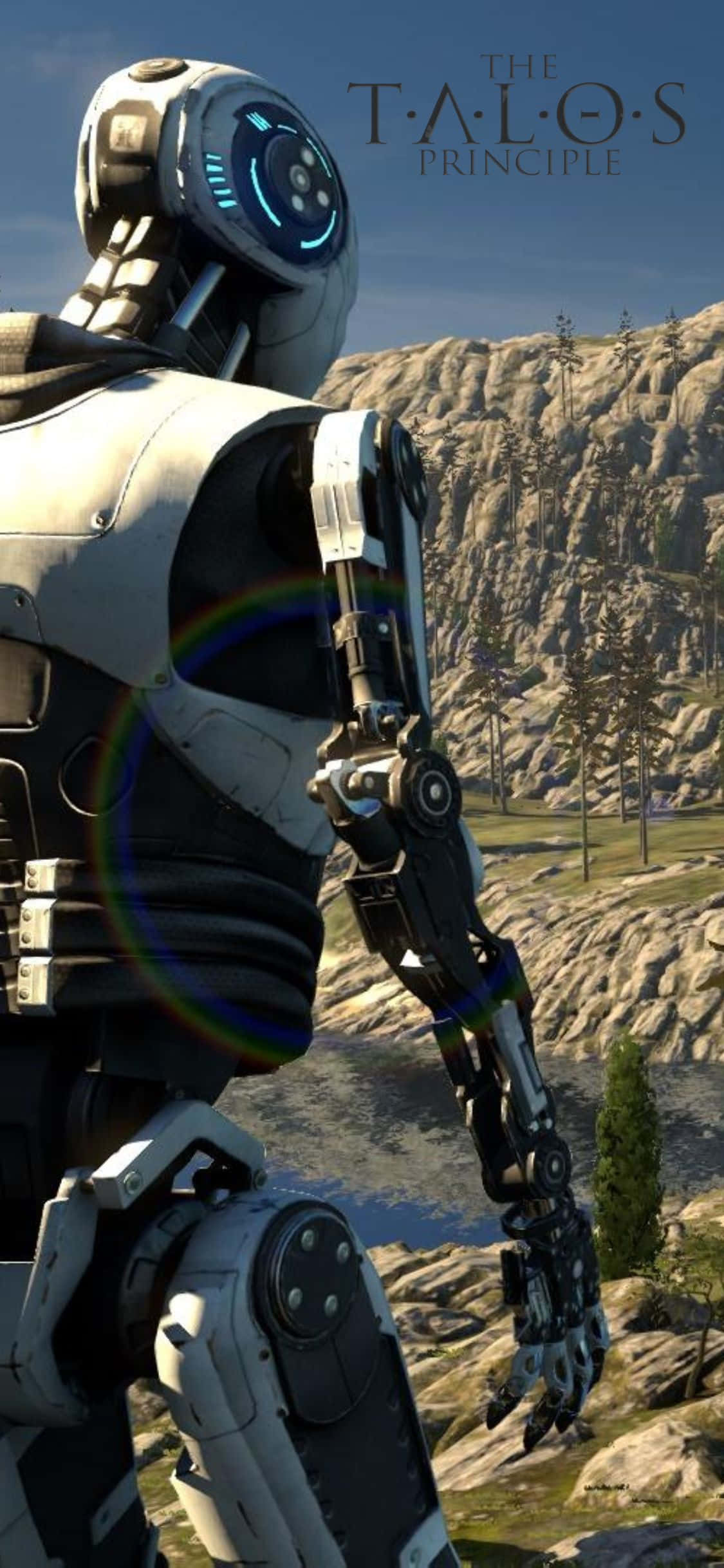 與 iPhone XS 版《The Talos Principle》進入神秘世界 壁紙 — 一個高聳的機械人站在岩石山區景觀中，天空清澈湛藍，帶有彩虹鏡頭光暈。