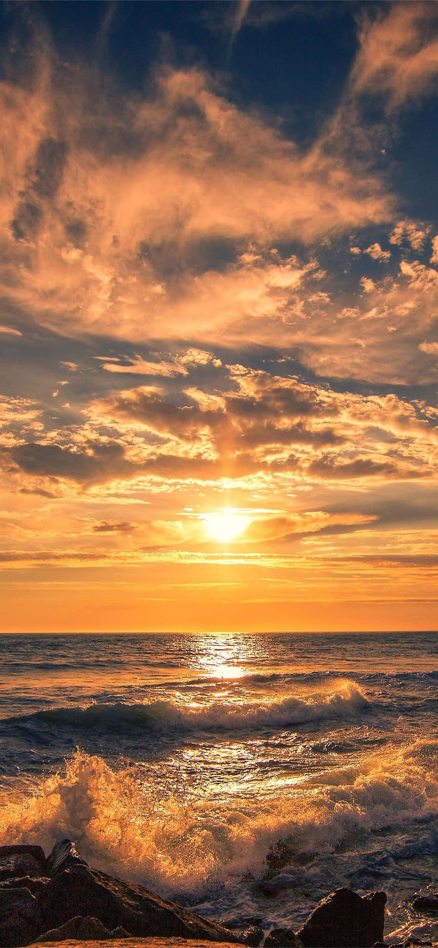 海洋上的夕陽，拍岸的海浪和黑暗的岩石