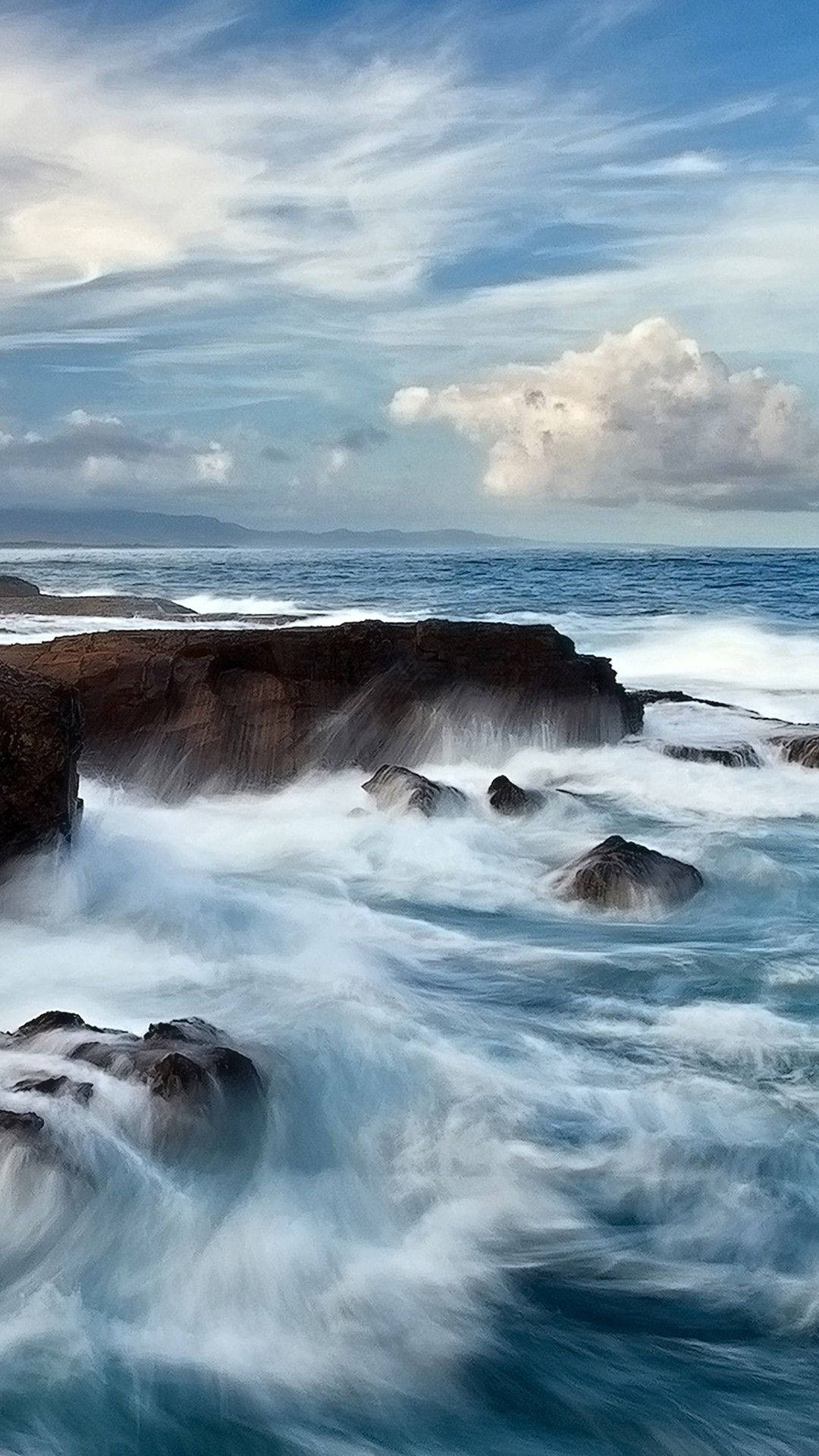 海浪在陰天下拍打著深色岩石