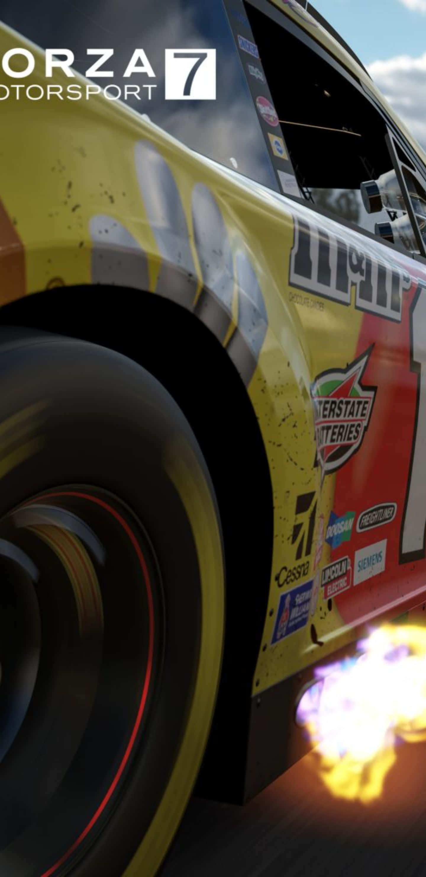 與 Pixel 3XL 和 Forza Motorsport 7 一同體驗高速賽車的快感 壁紙 — 一輛帶有贊助商貼紙的黃色賽車在晴朗的天空下高速過彎，排氣管噴出火焰。