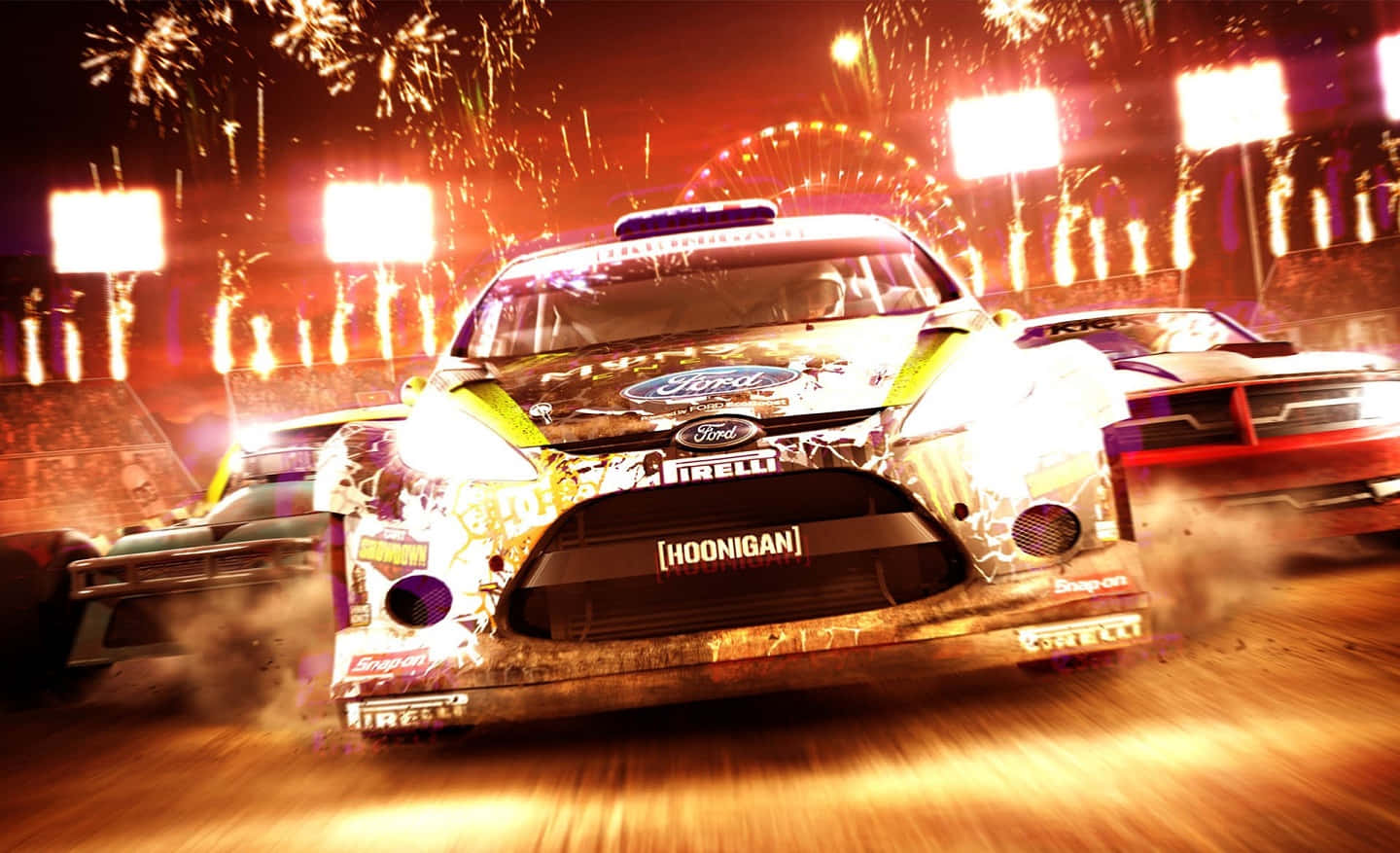 與《泥地對決》一同駛向夕陽 壁紙 — 一輛帶有 'Hoonigan' 品牌的福特拉力賽車在煙火和體育場燈光下於夜間賽道上飛馳。